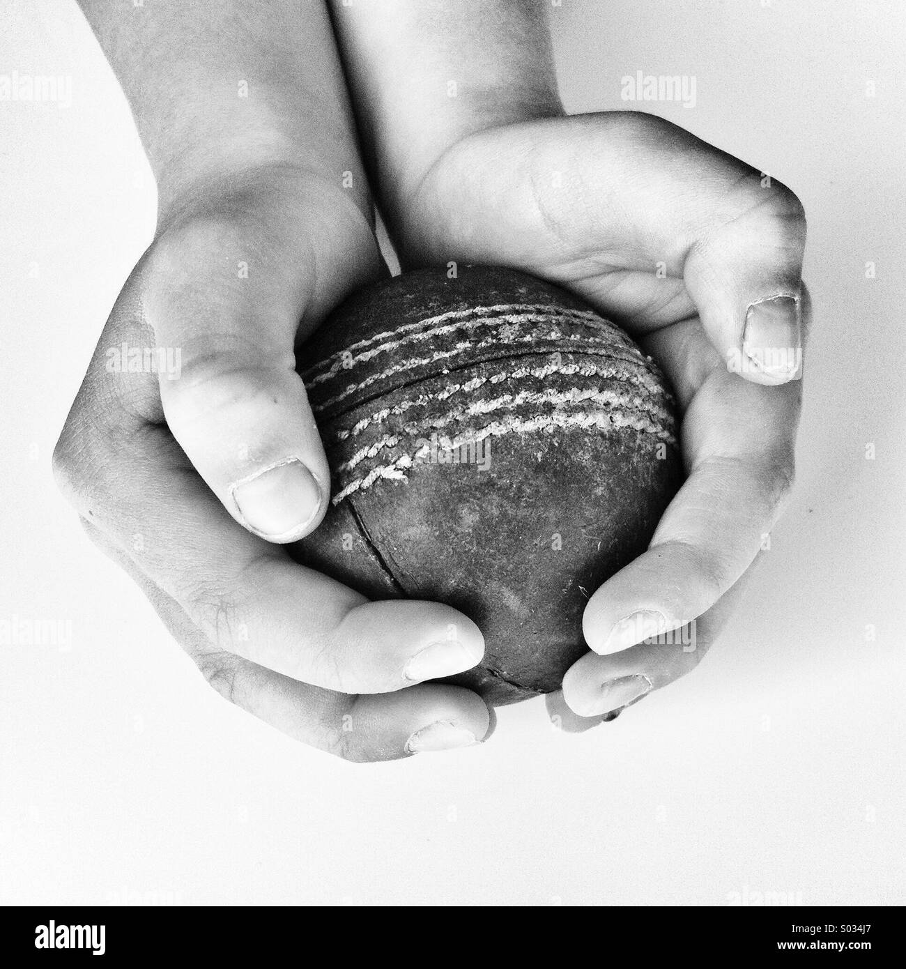 Jungen Händen umklammert ein Cricketball Stockfoto