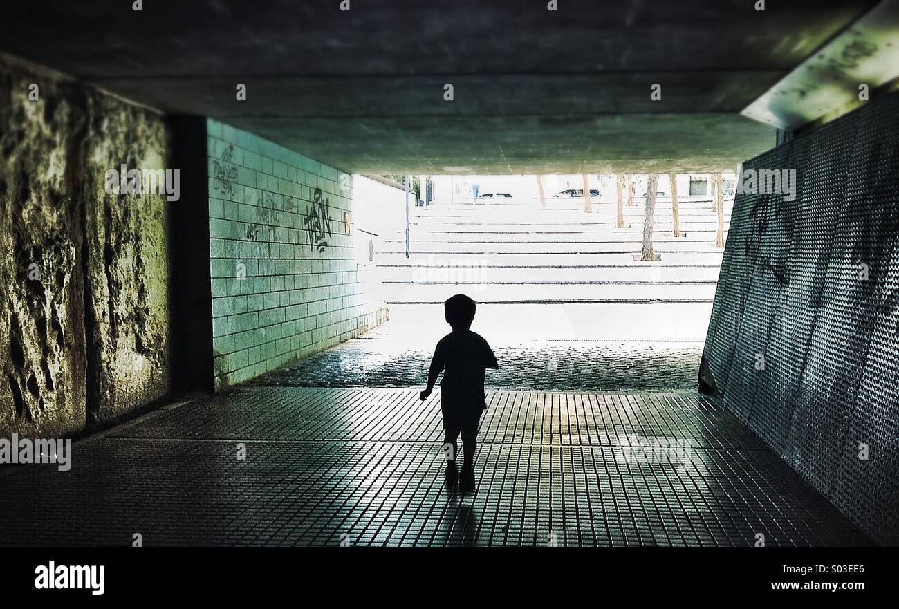 Silhouette einer Person zu Fuß durch eine dunkle Unterführung symbolisiert Licht am Ende des Tunnels Stockfoto