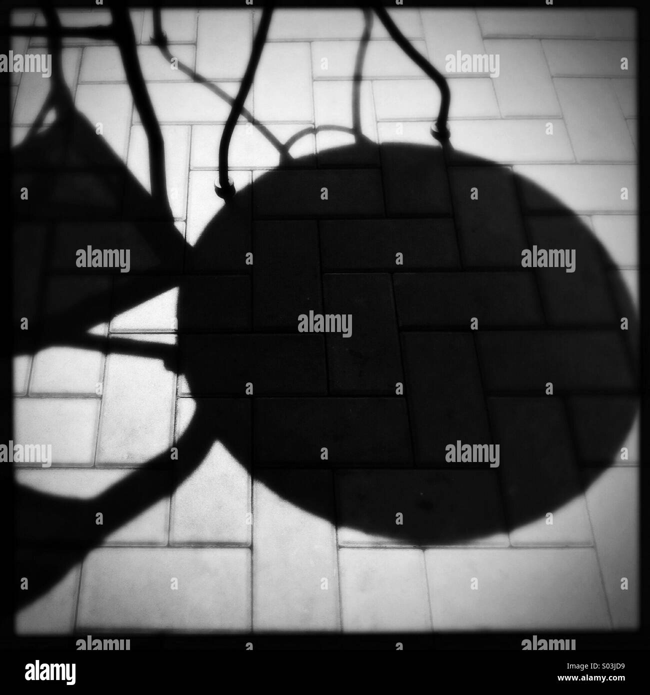 Harte schwarze Schatten von Gartenmöbeln keine Stimulation Steine außerhalb eines Cafe an einem sonnigen Tag. Stockfoto