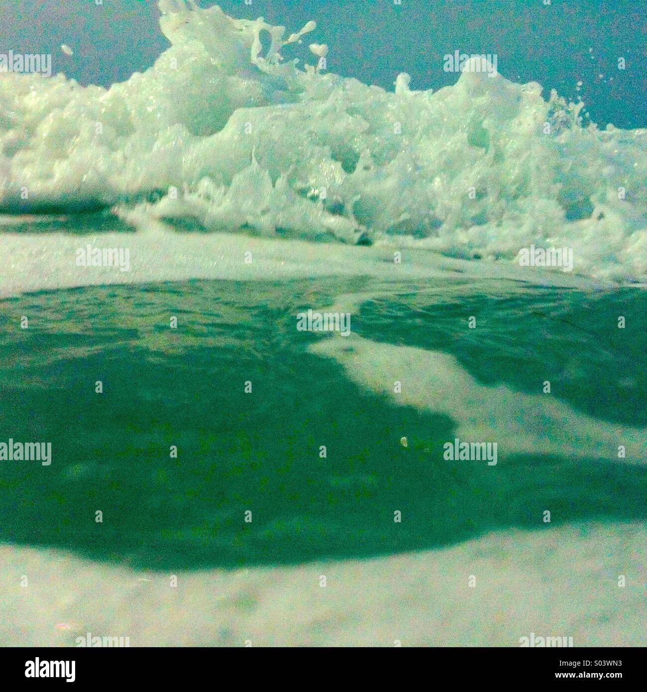 Weiße Wasser aus einer brechenden Welle rollt in Ufer. Stockfoto
