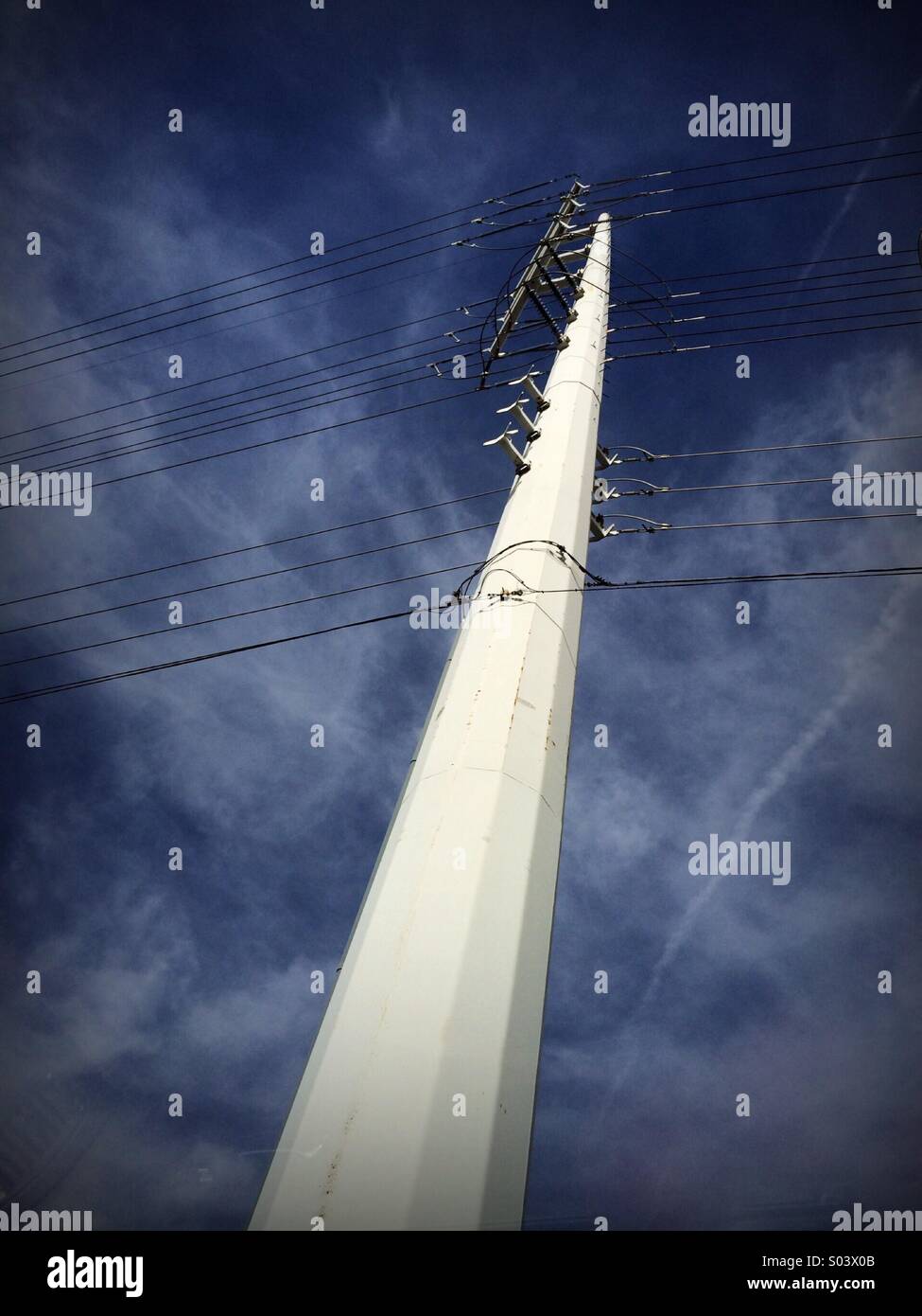 Stromleitungen zu einem Schnäppchen Lichtleistung farbige Pfosten befestigt kontrastiert eine leicht bewölktem Himmel - Smartphone-aufgenommenes Stockfoto