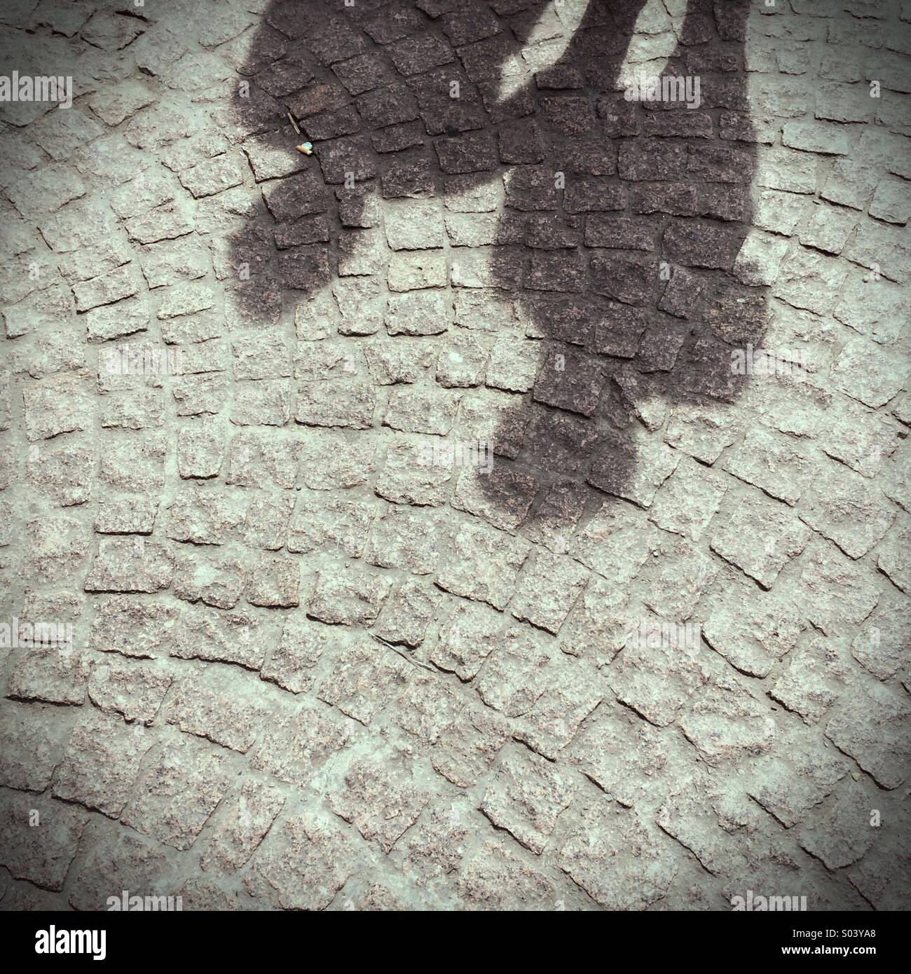 Der Schatten von zwei Menschen auf einer gepflasterten Straße Stockfoto