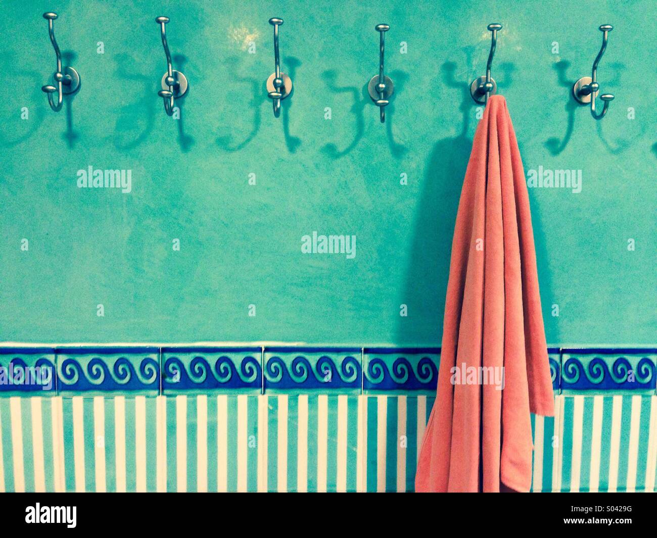 Orange Handtuch aufhängen an einem Haken gegen türkisfarbenen Wand Stockfoto
