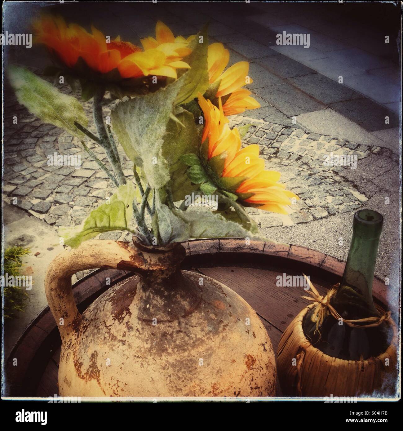 Sonnenblumen im alten altmodischen Wasser Tonkrug neben Stil Flasche Chianti. Stockfoto