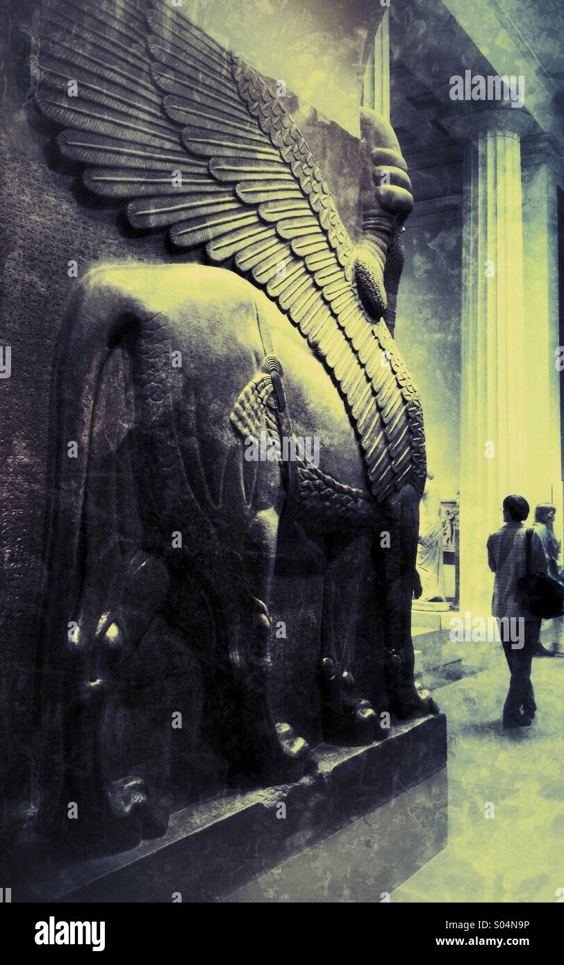 Eine Frau erforscht eine Galerie des British Museum in London, mit einer kolossalen Assyrian Statue eines geflügelten Löwen vom Palast Eingang des König Ashurnasirpal ihr überragt. Stockfoto