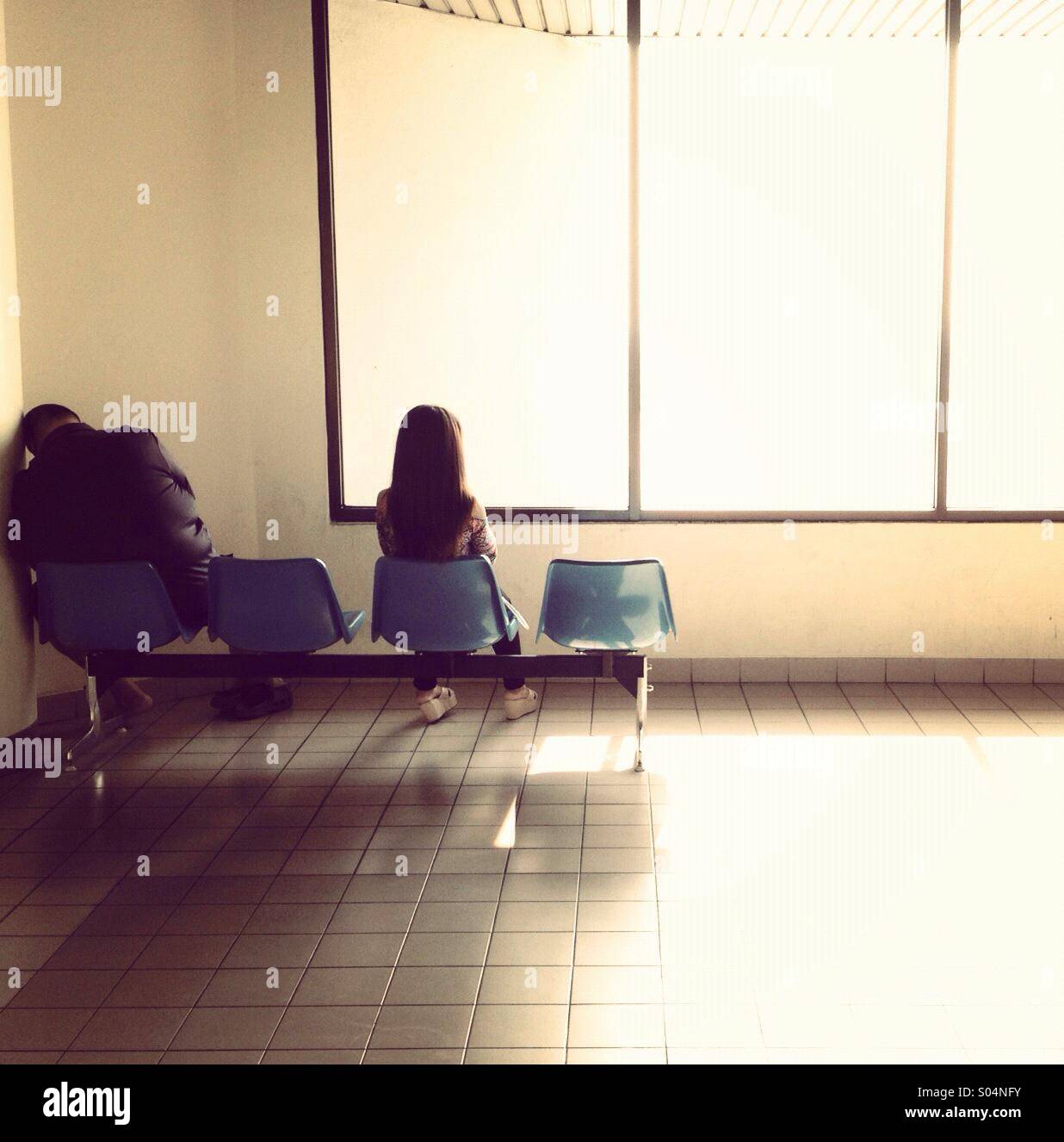 Allein und niedergeschlagenen Flughafen Wartezimmer sitzen auf harten Plastikstühlen Stockfoto