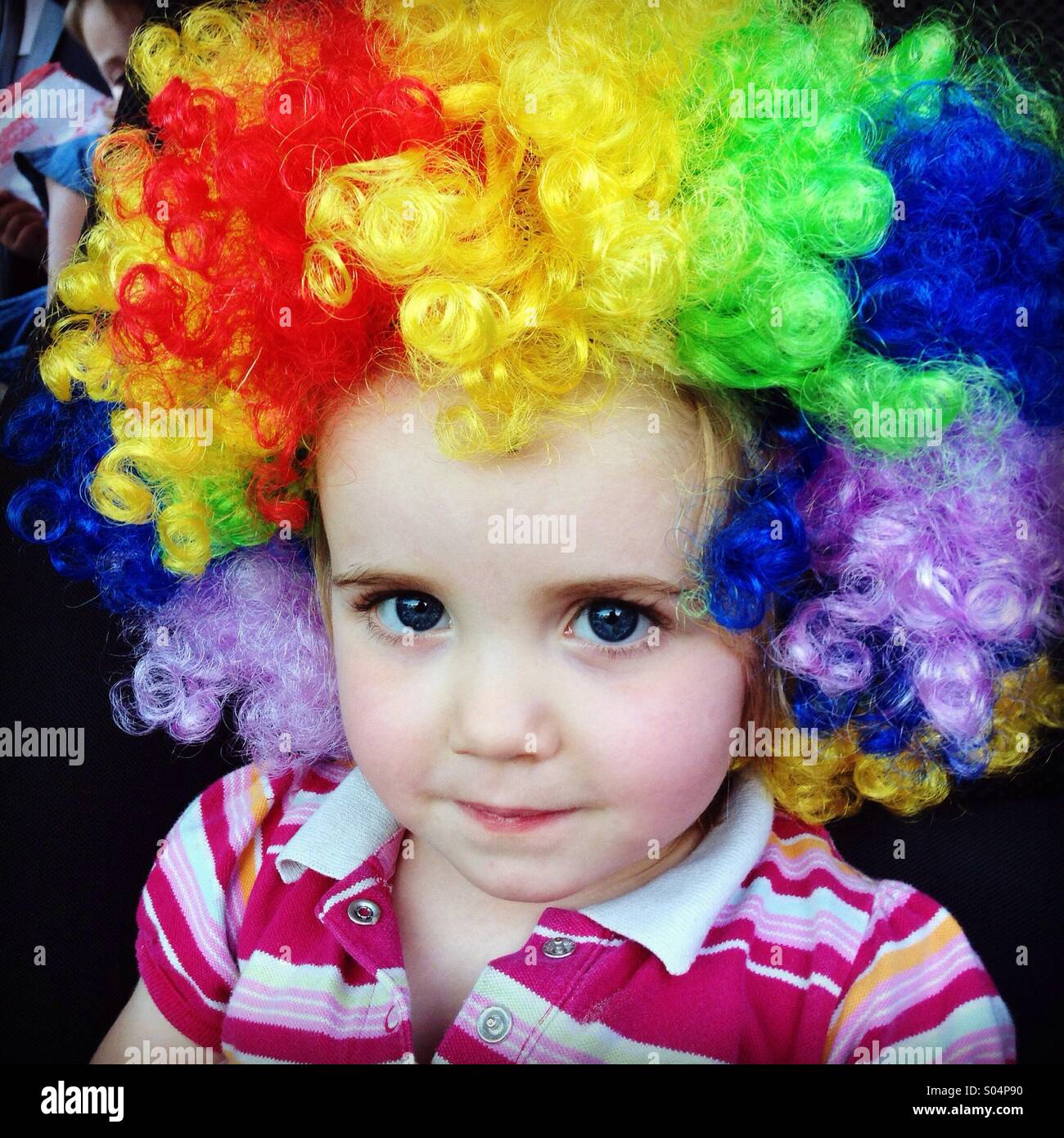 Kleines Mädchen mit Regenbogen Clown Perücke Stockfoto