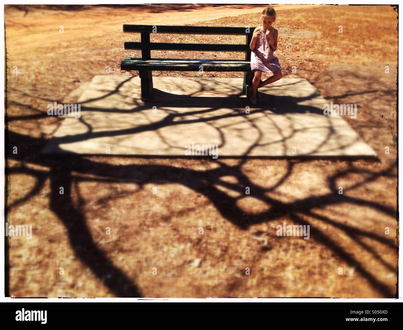 Kleines Mädchen auf einer Parkbank. Stockfoto