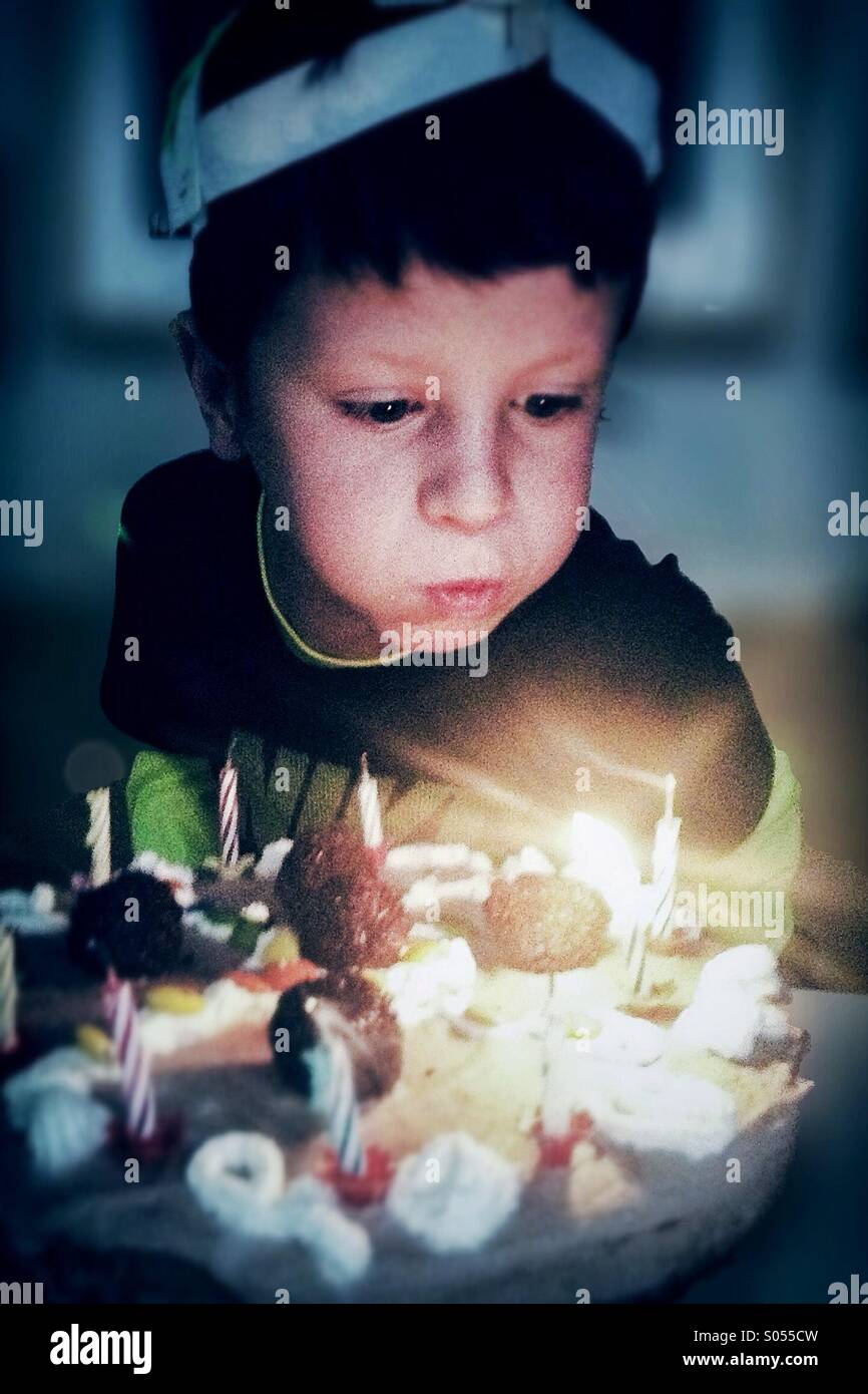 Junge feiert seinen Geburtstag und Ausblasen der Kerzen auf dem Kuchen Stockfoto