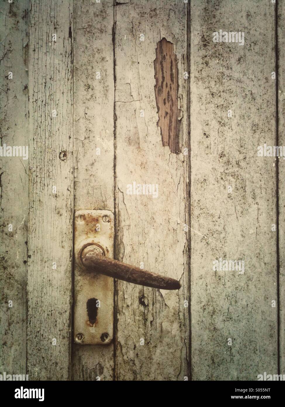 Alte Türklinke auf Holztür mit abblätternde Farbe. Stockfoto