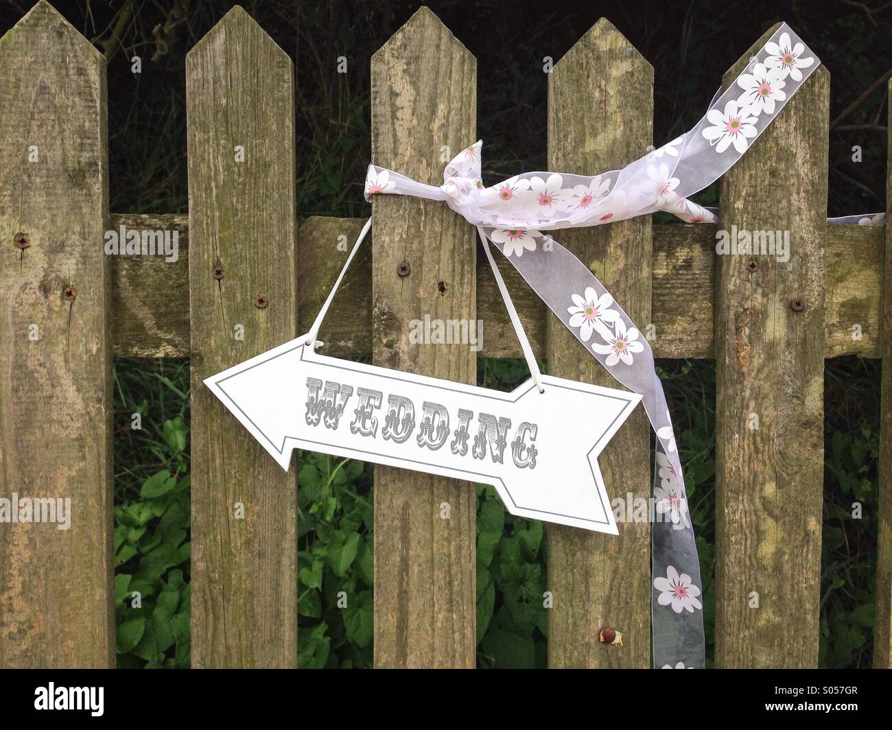 Hochzeit-Pfeil-Symbol an einem Zaun hängen - Smartphone-aufgenommenes Stockfoto