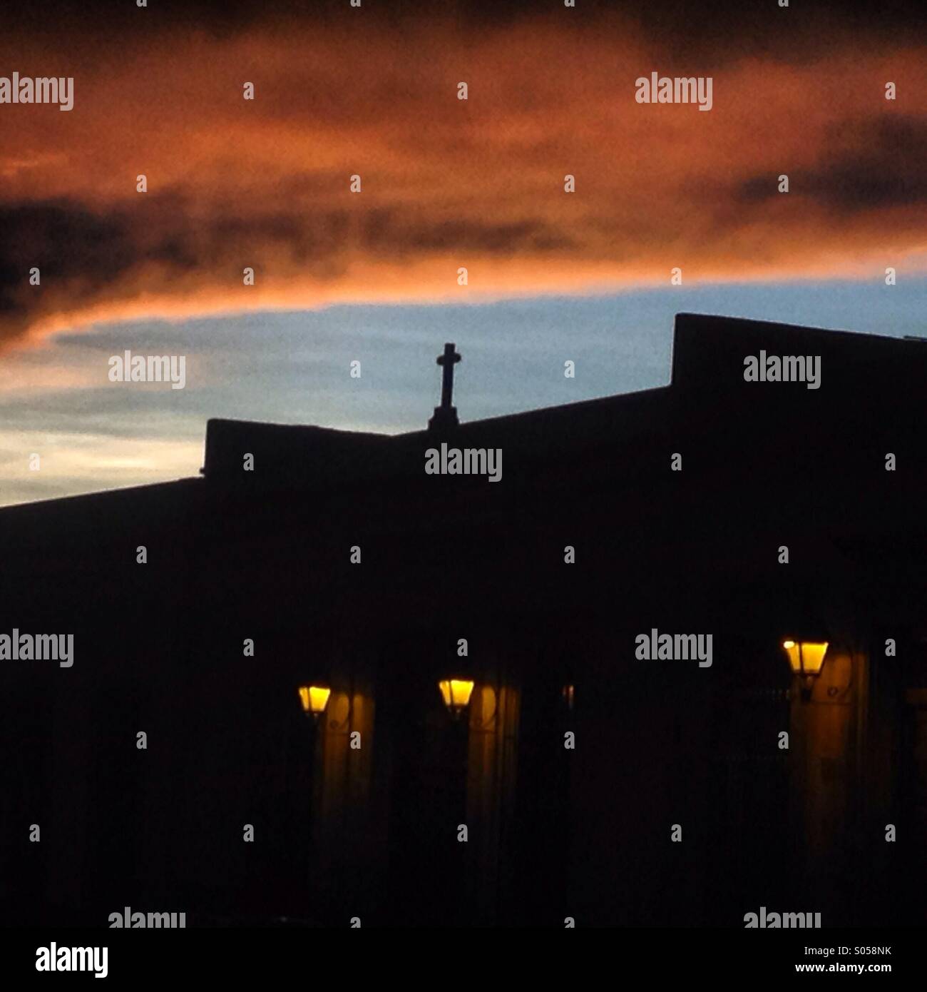Ein Kreuz ziert eine Haus im koloniale mit Straßenlaternen beleuchtet bei Sonnenuntergang in Queretaro, Mexiko. Stockfoto