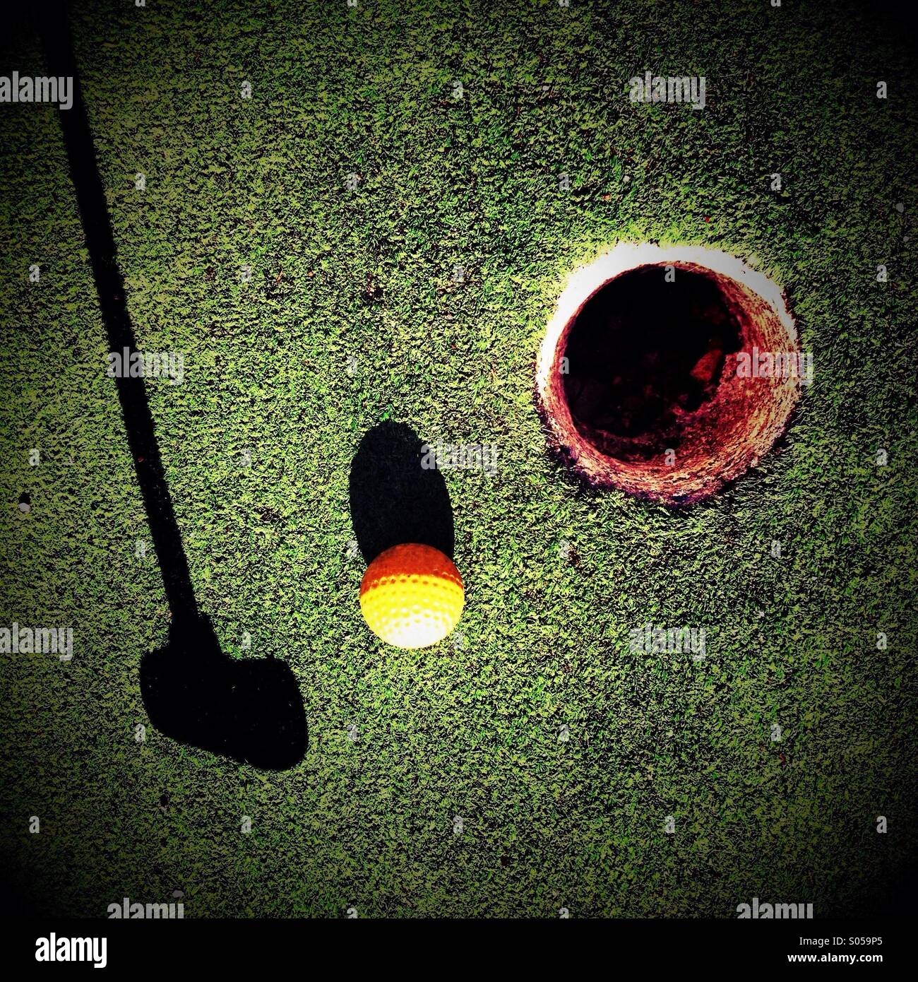 Schatten-Putter Golfball in Richtung Loch schlagen Stockfoto