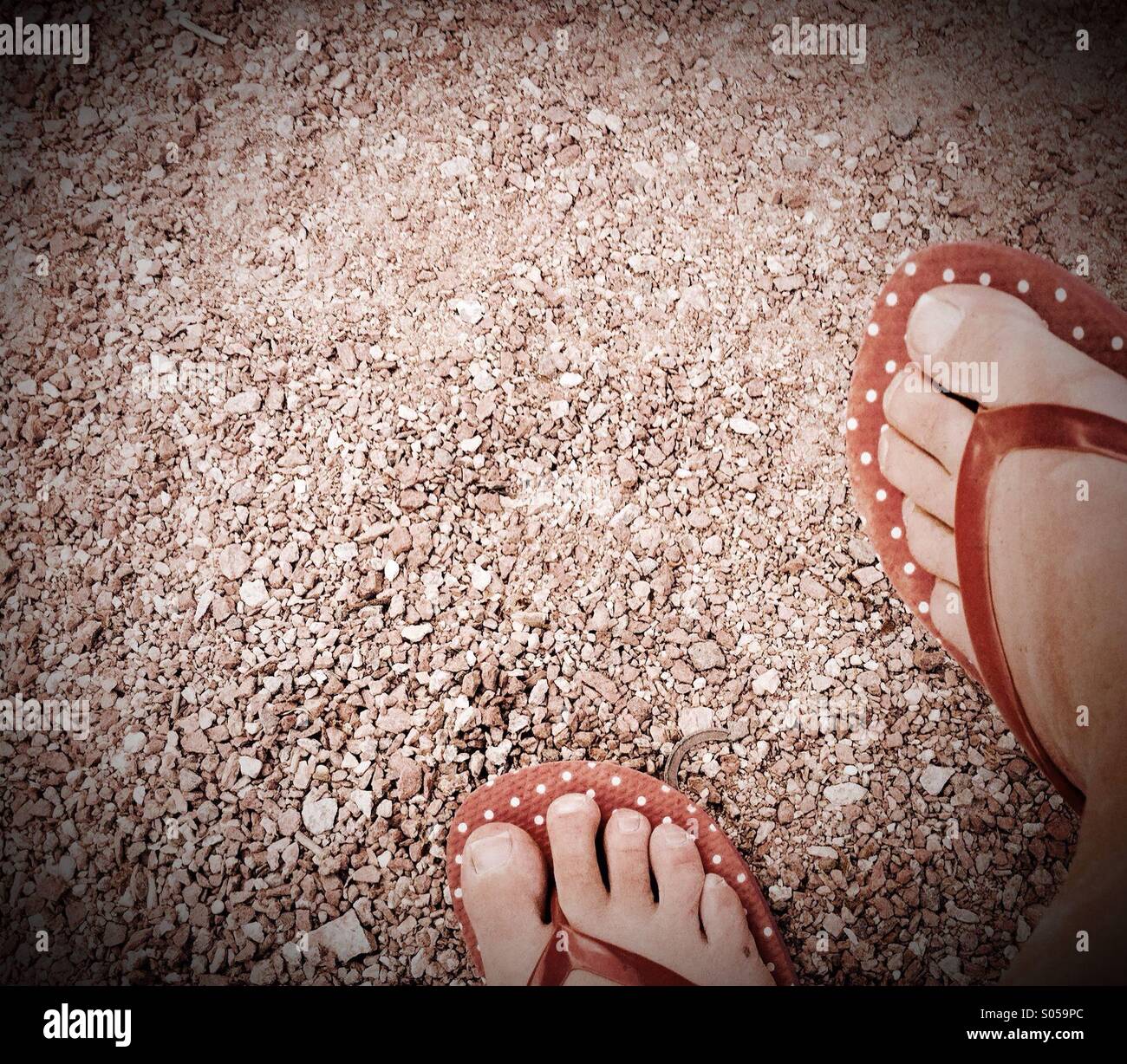 Füße mit roten Flipflops auf sand Stockfoto