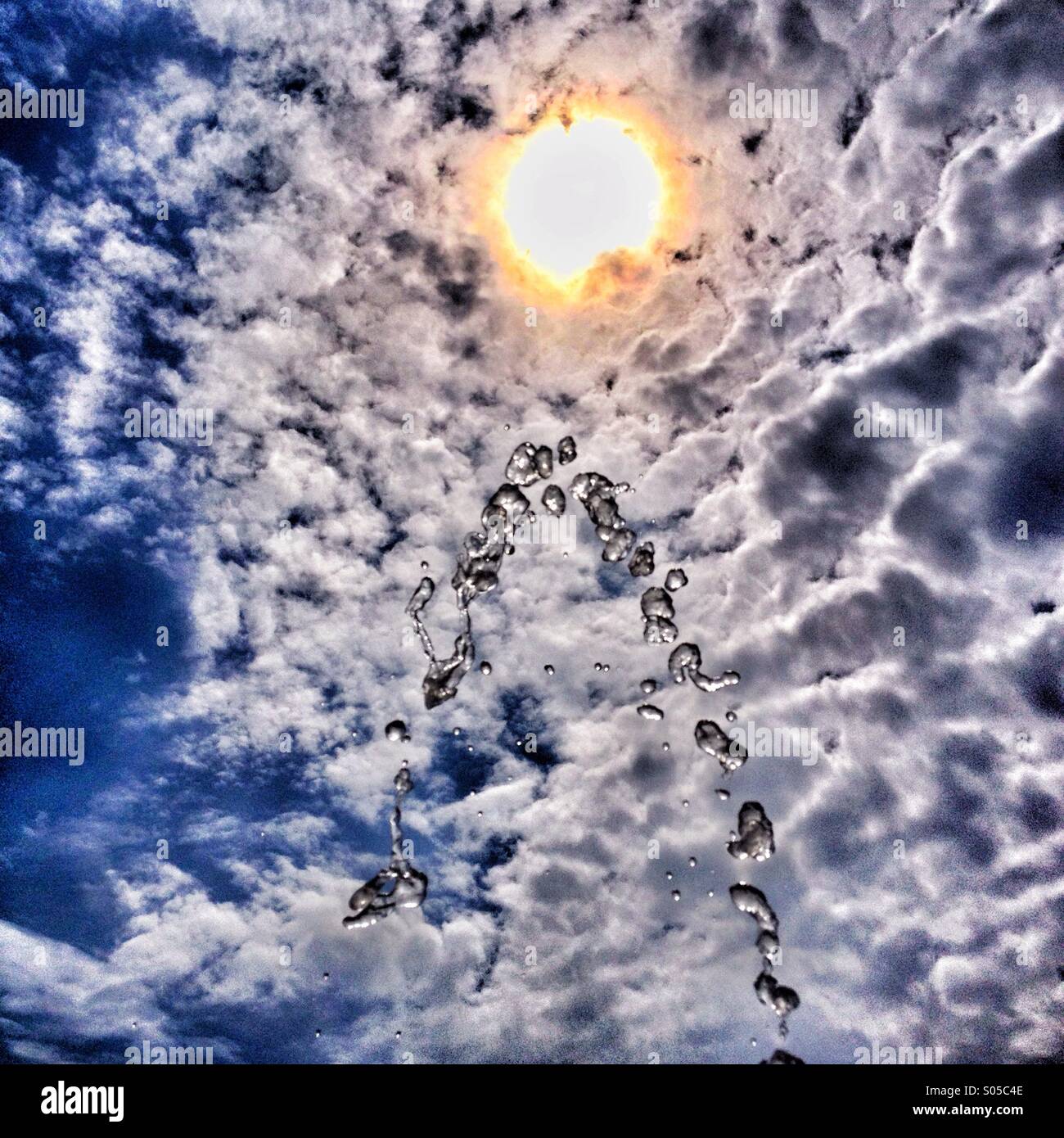 Wasser-Brunnen Hintergrundbeleuchtung durch Sonne gegen dramatische Wolken - Smartphone-aufgenommenes Stockfoto