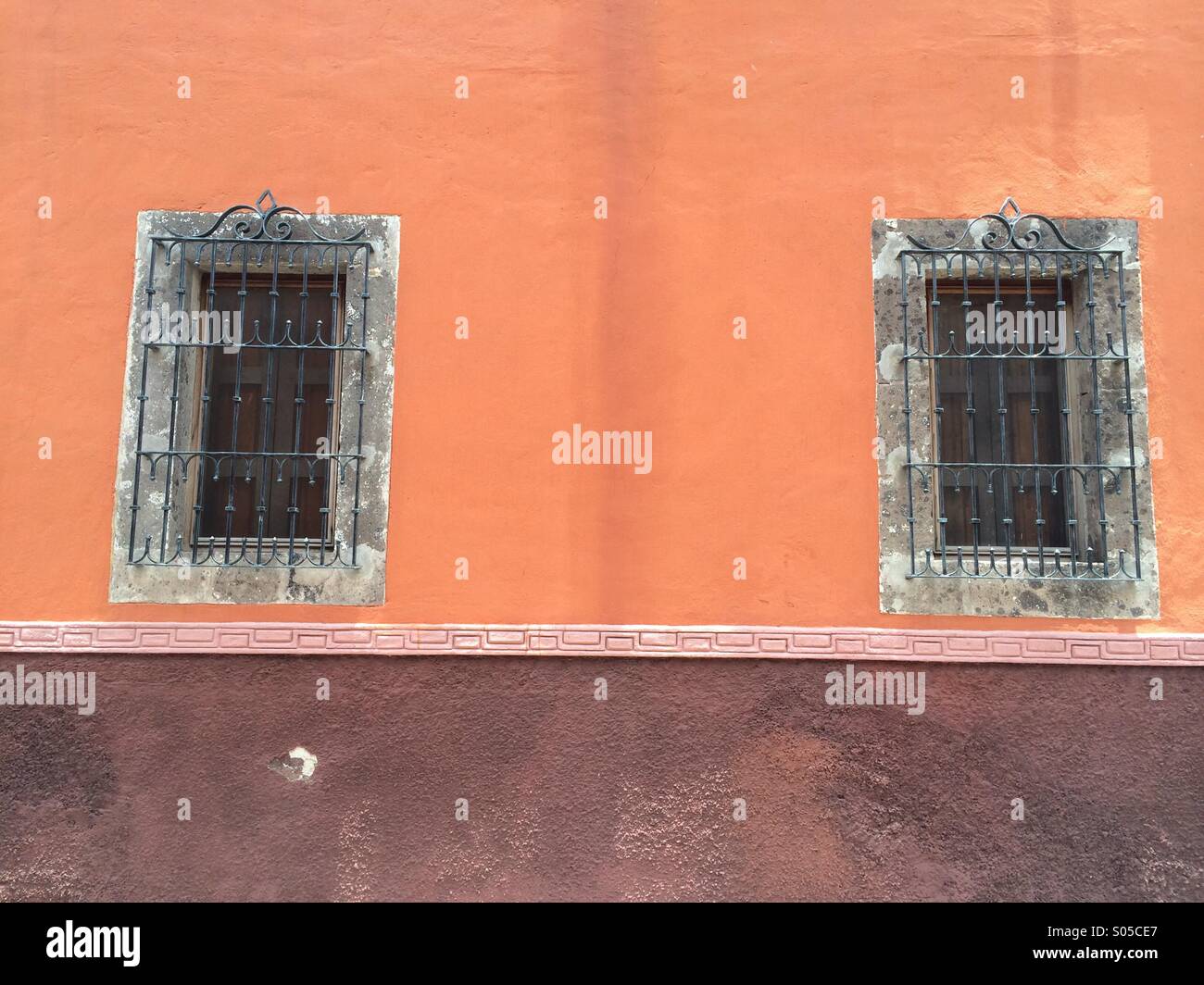 Zwei Fenster auf steinernen Rahmen und Eisenstangen auf einem alten Kolonialhaus mexikanische Stockfoto