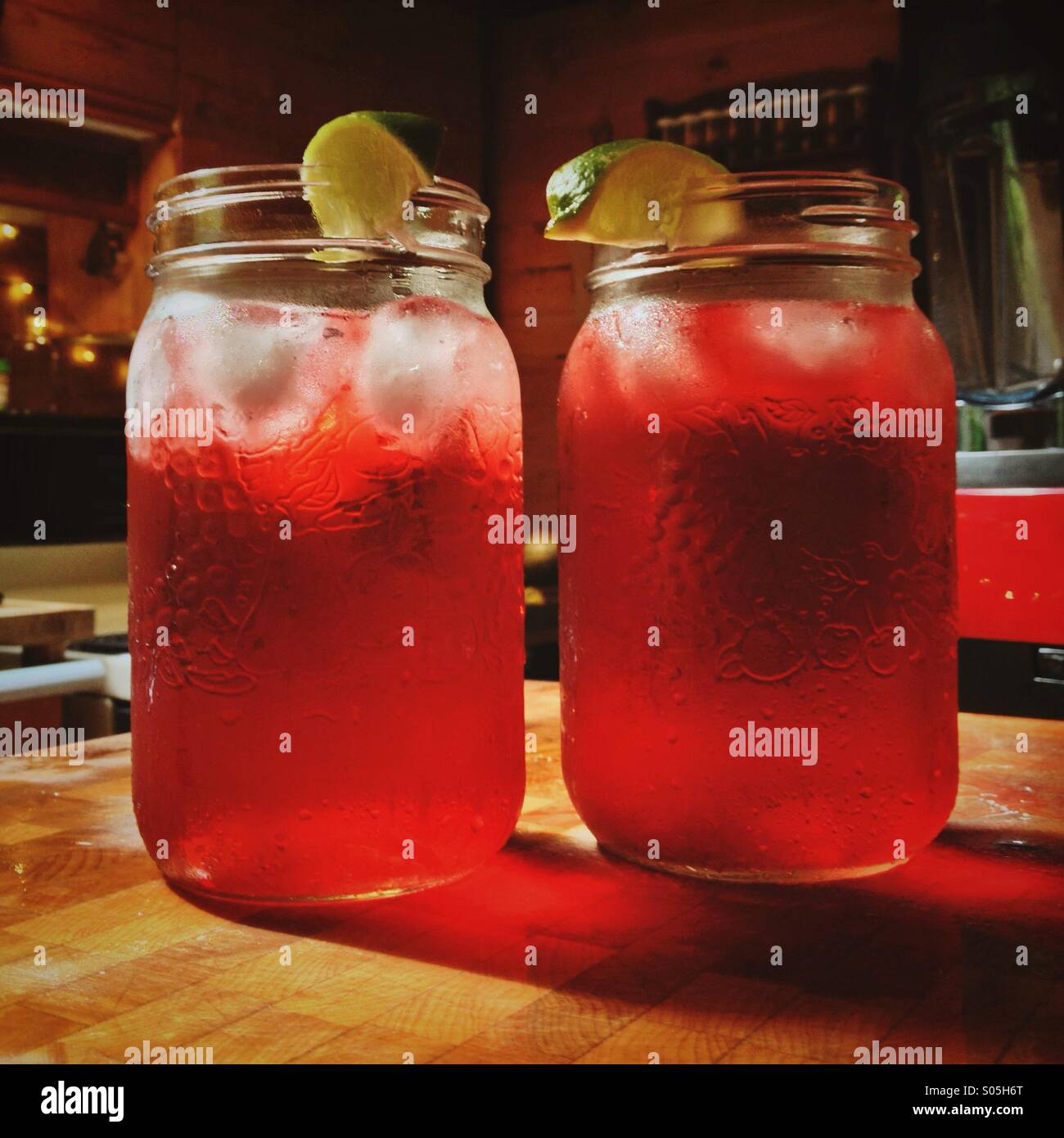 Zwei große Gläser Rot iced Hibiskus Teegetränke auf Hackklotz in Küche Stockfoto