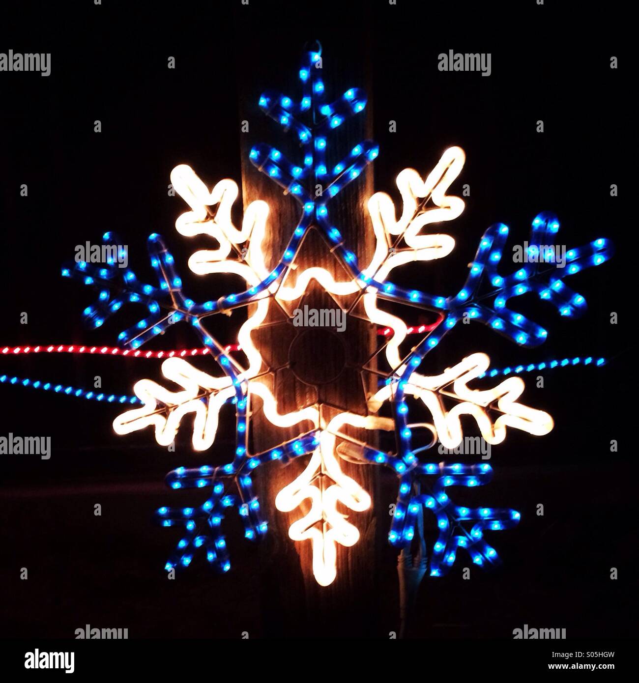 Leuchtende LED Deko Schneeflocke vor weissem Hintergrund Stock