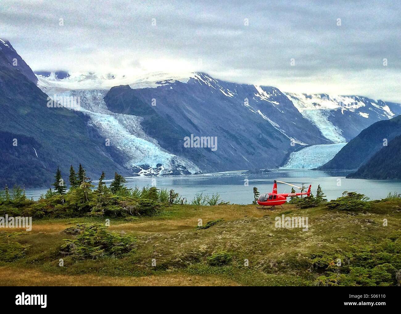 Ansicht eines Hubschraubers, Robinson R44 geparkt vor dem Cox und Barry Gletscher in Harriman Fjord im Prinz-William-Sund, Yunan Alaska, Sommer. Stockfoto