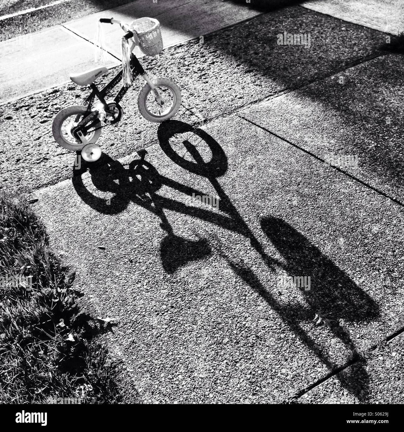 Fahrrad auf Bürgersteig mit Schatten. Stockfoto