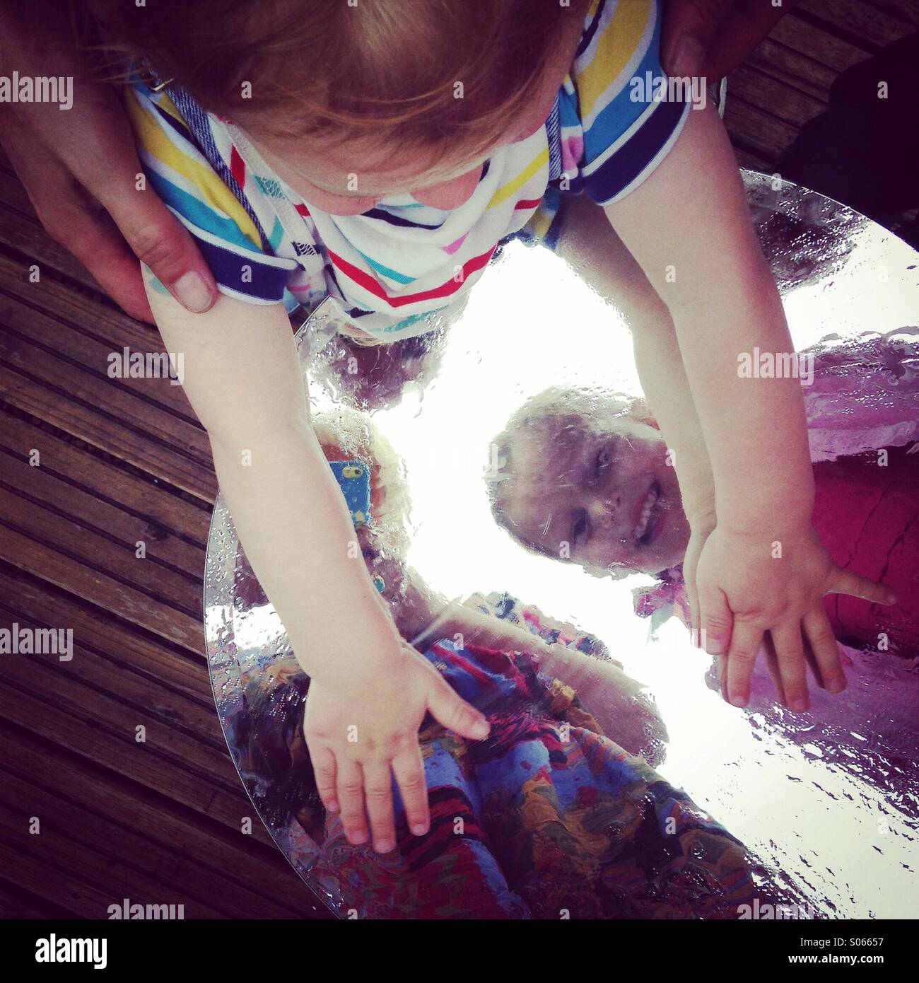 Kinder spielen mit Reflexionen über einen Tisch draußen im Sommer. Stockfoto