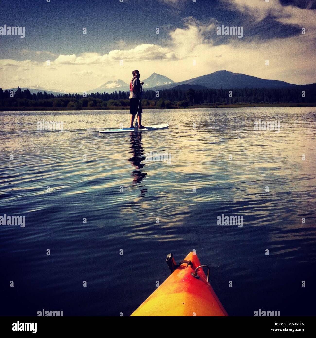 Junge auf Paddleboard auf See in Bergen. Stockfoto