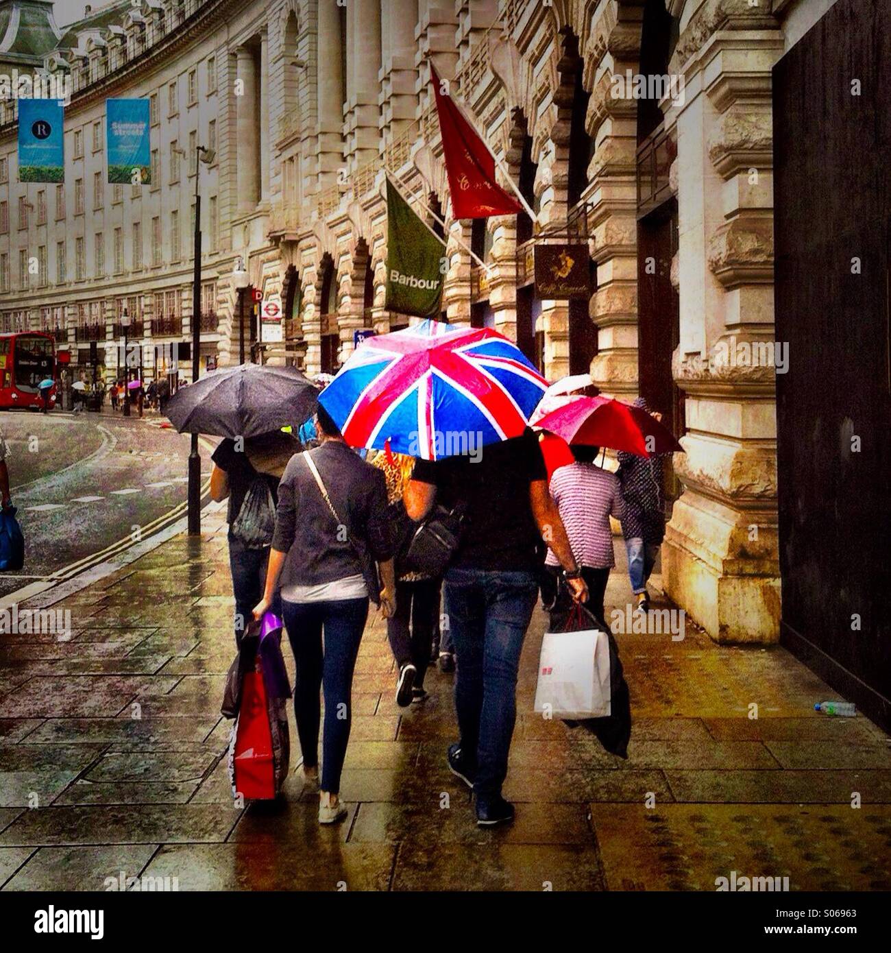 Die Menschen gehen auf Regent Straße an einem regnerischen Tag. London England UK. Stockfoto