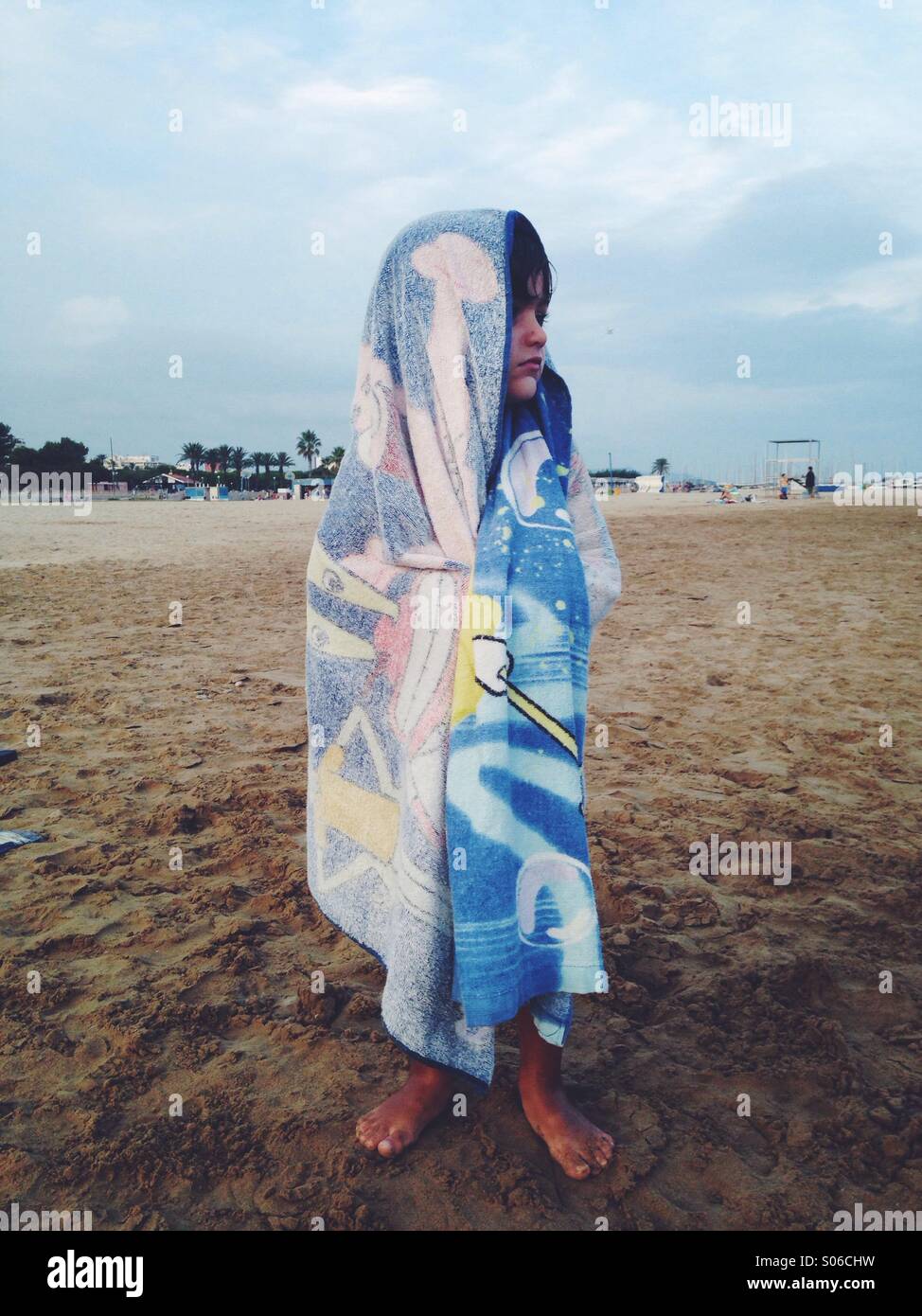 Drei Jahre alter Junge mit einem Handtuch am Strand bedeckt Stockfoto