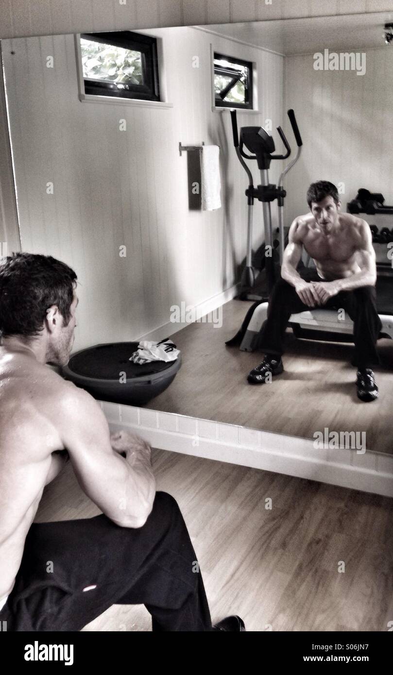 Fitness - muskulöser Mann in einem Fitnessstudio, sitzen vor einem Spiegel Stockfoto