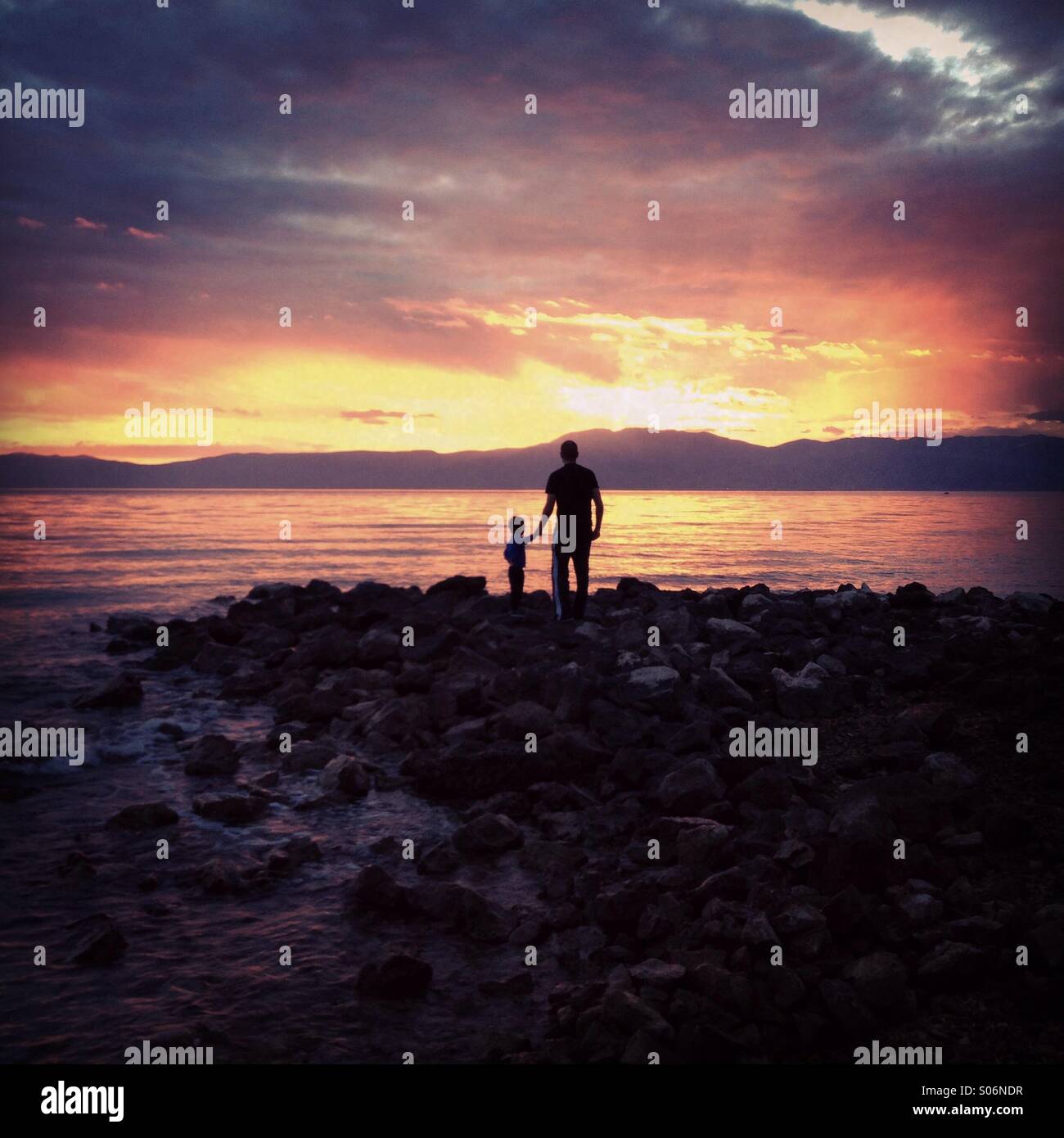 Vater und Sohn am Meer bei Sonnenuntergang Stockfoto