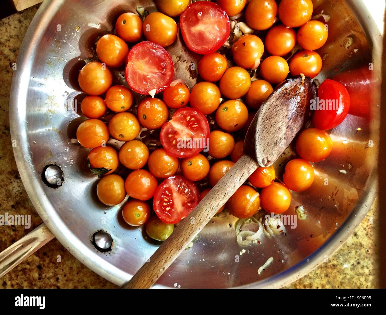 Erbstück-Tomaten in einer Pfanne mit einem Holzlöffel Stockfoto