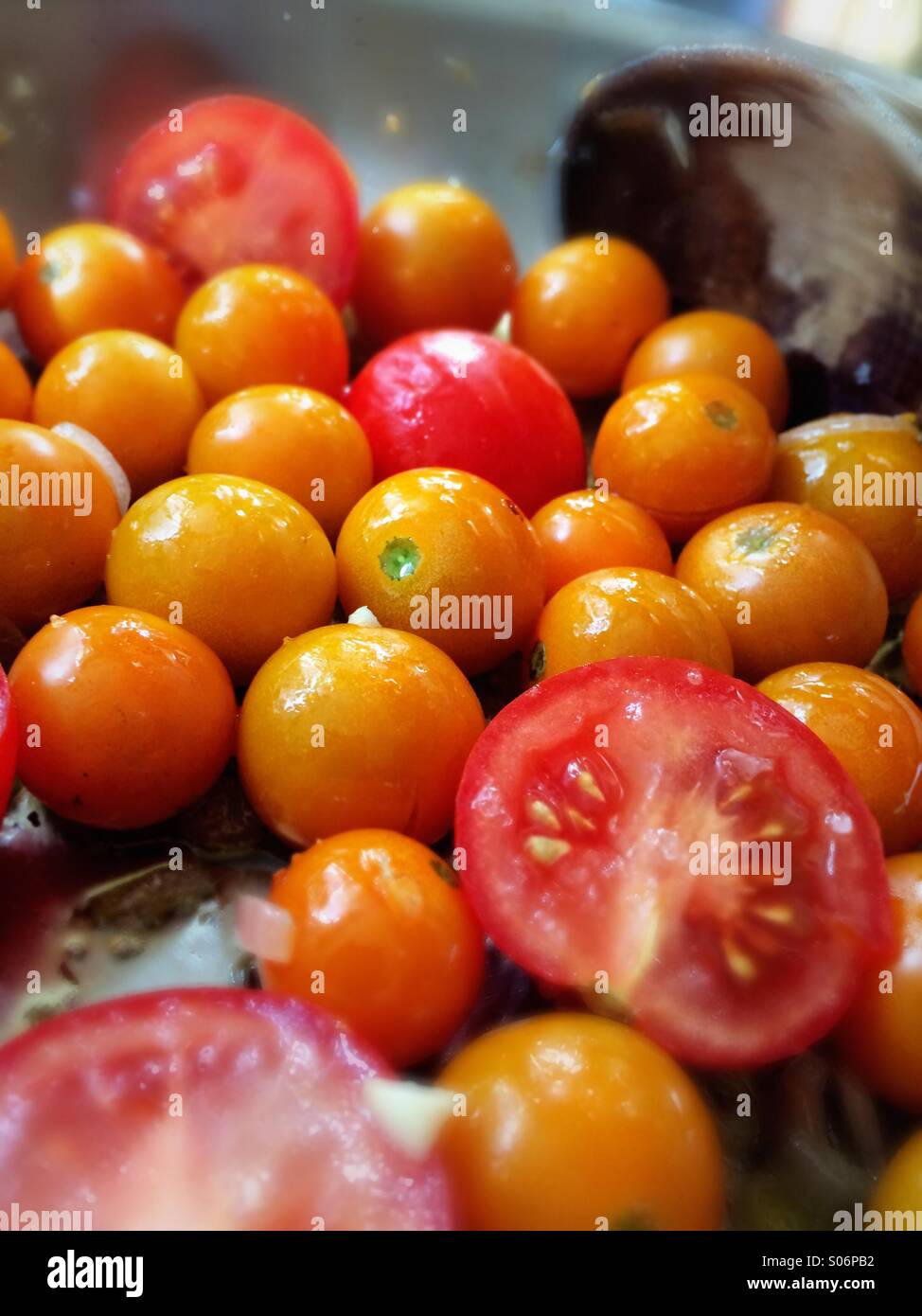 Erbstück-Tomaten in eine Bratpfanne Pfanne mit Olivenöl und Knoblauch Stockfoto