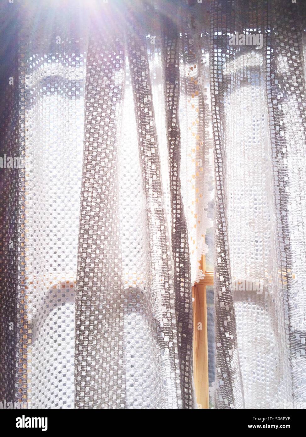 Gardinen in einem Fenster mit streaming Sonnenlicht. Stockfoto