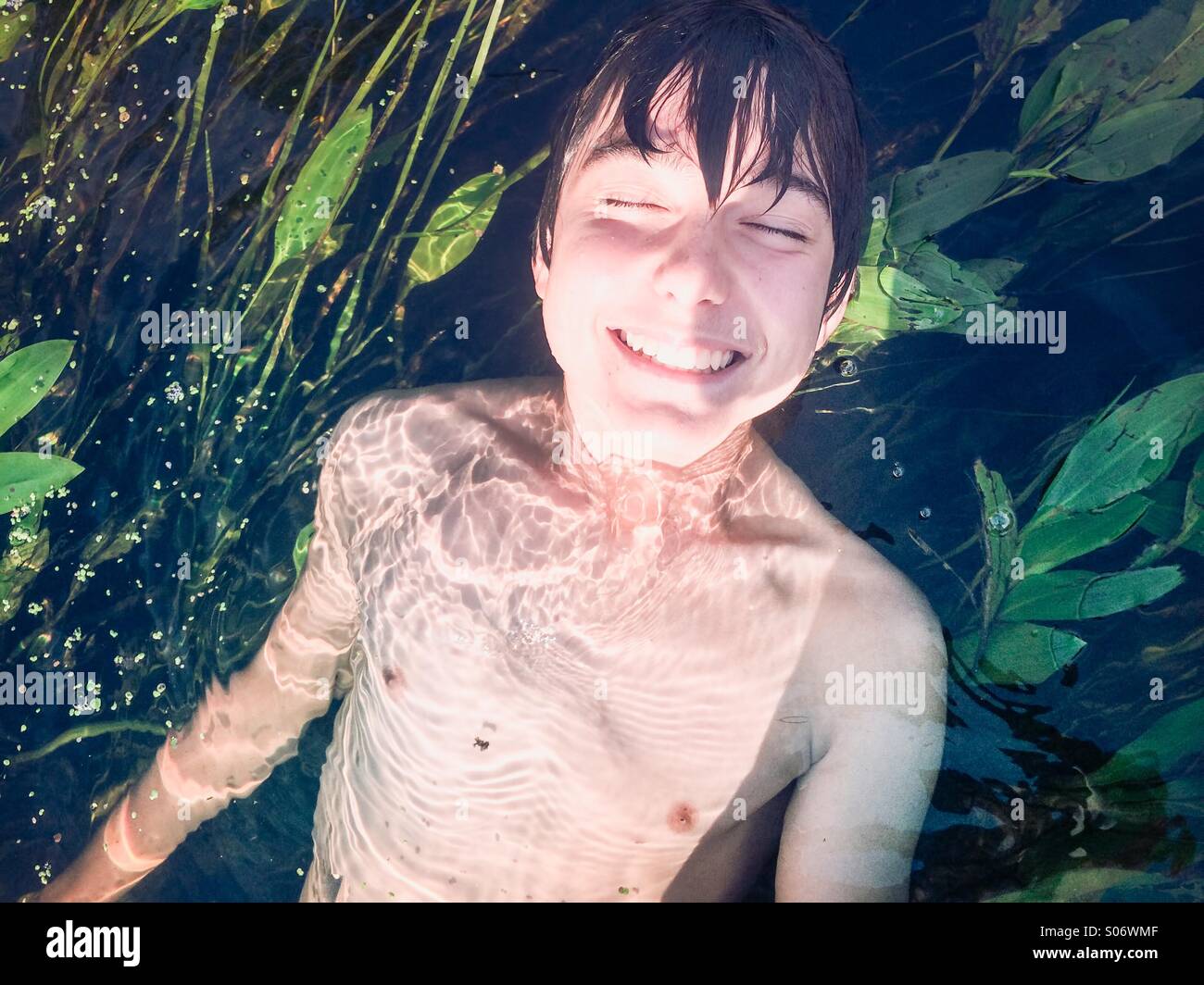 Lächelnde junge in einem reinen Fluss getaucht. mit üppigem Grün Stockfoto