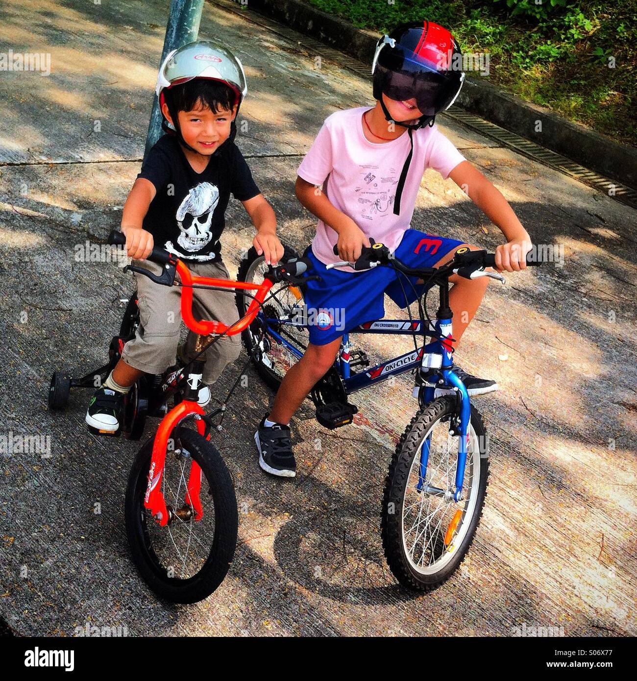 Zwei Brüder bereit zum Radfahren. Es Helm - Smartphone-aufgenommenes Stockfoto