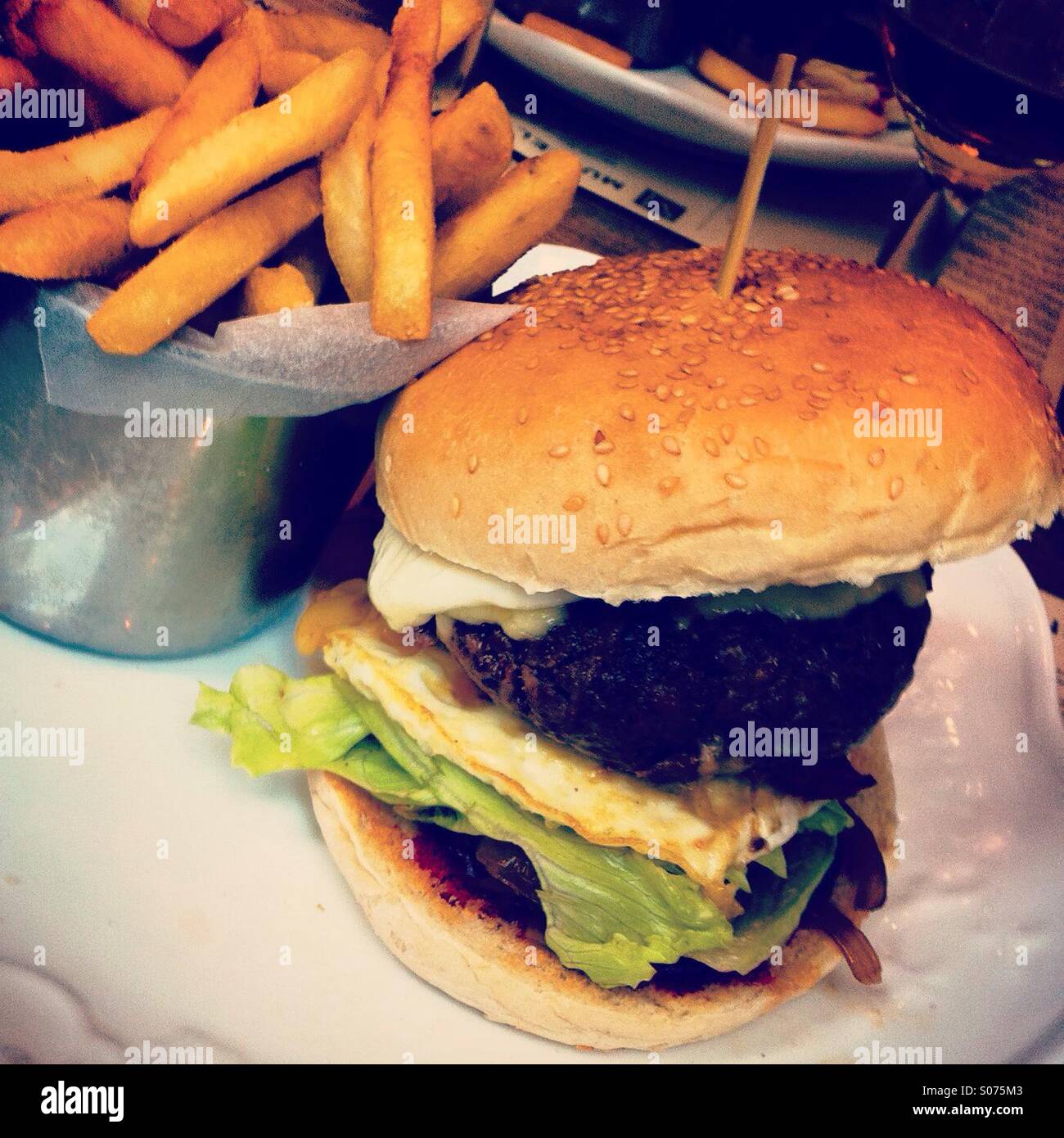 Leckere Burger mit Pommes frites bereit, gegessen zu werden - Smartphone-aufgenommenes Stockfoto