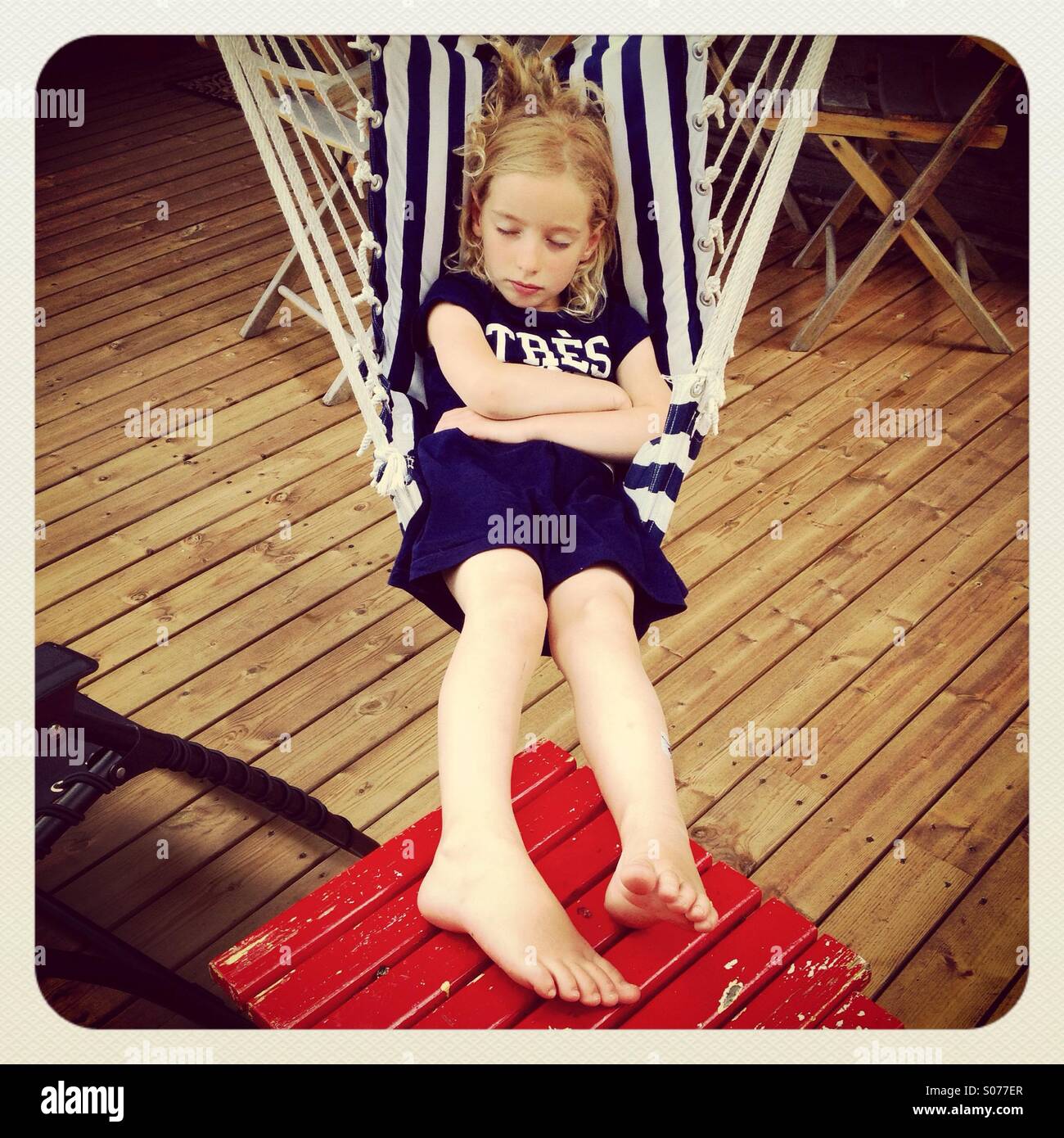 Ein junges Mädchen im Urlaub in einer nordischen Sommerhaus Hängematte schlafen Stockfoto
