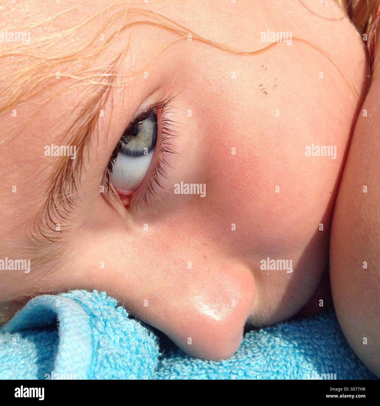 Eine Nahaufnahme des Gesichts eines jungen Mädchens entspannen Sie sich auf ein Strandtuch bei einem Familienurlaub Stockfoto