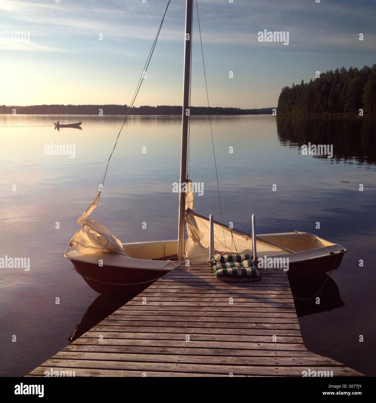 Ein Segelboot und ein Fischerboot auf einem idyllischen nordische See im Norden von Finnland Stockfoto