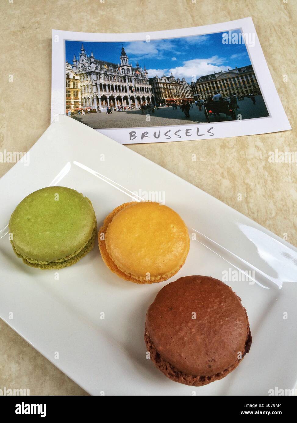 Grüße aus Brüssel mit drei Macarons und eine Postkarte - Smartphone-aufgenommenes Stockfoto