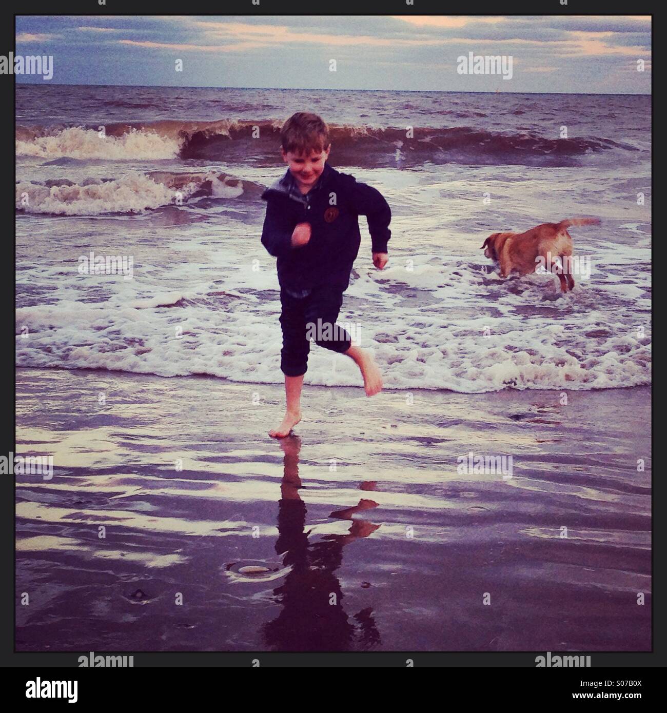 Am Abend Spaß Paddeln im Meer. Junge und Hund. Hornsea. Stockfoto