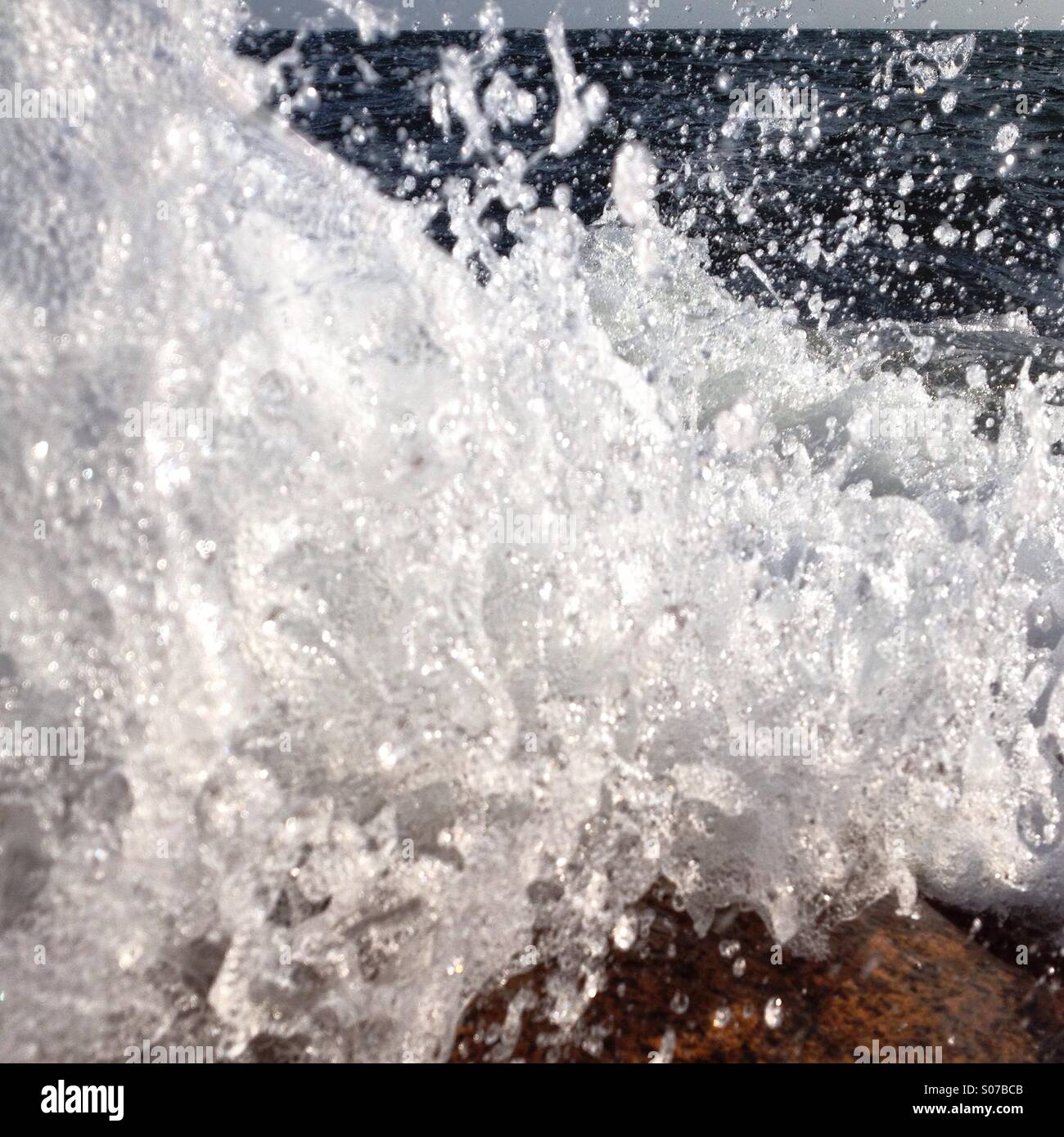 Eine Welle an Felsen gefangen im letzten Moment bevor es das Objektiv trifft brechen Stockfoto