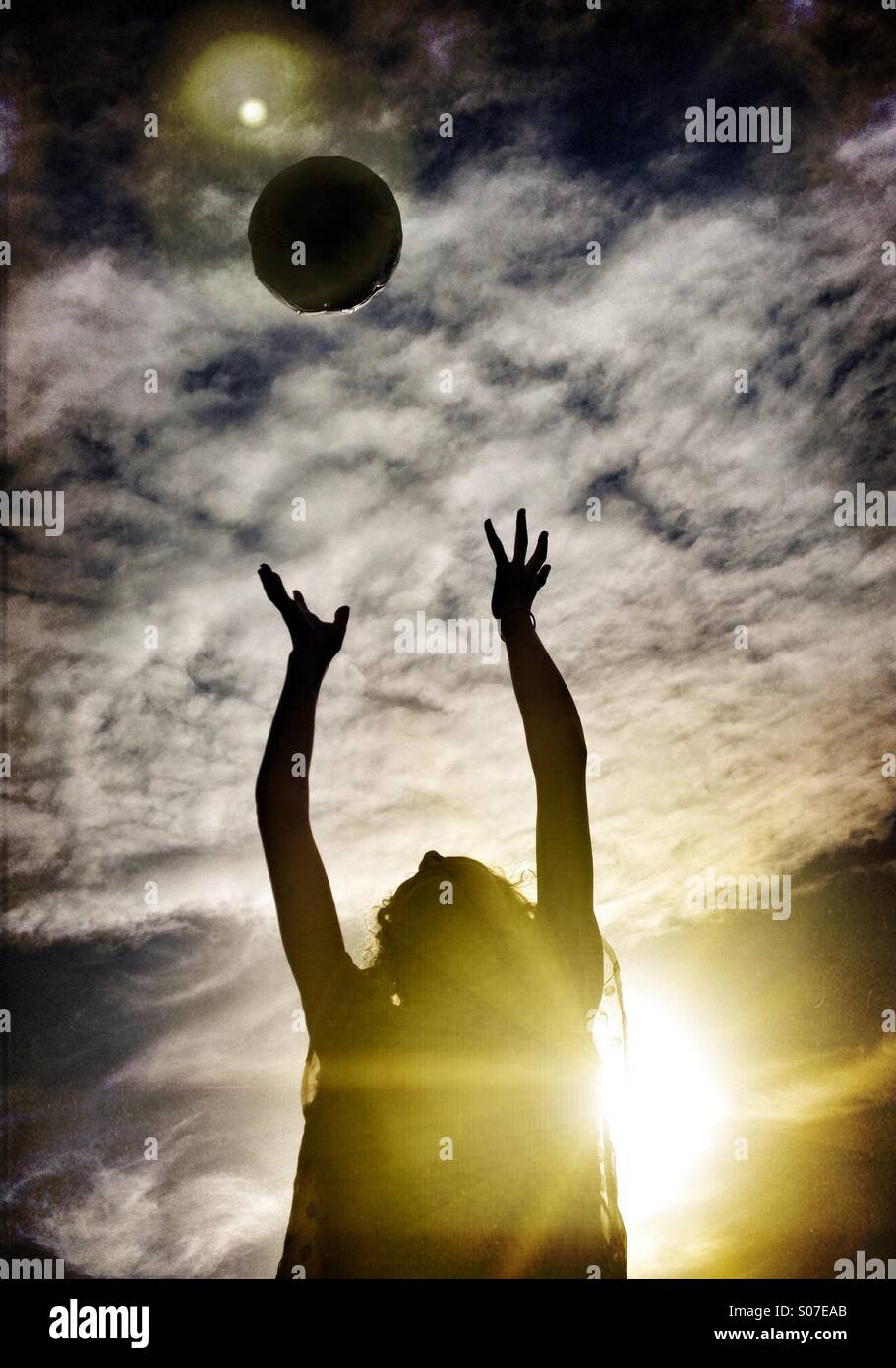 Junges Mädchen fangen Fußball Hintergrundbeleuchtung durch Sonne Stockfoto