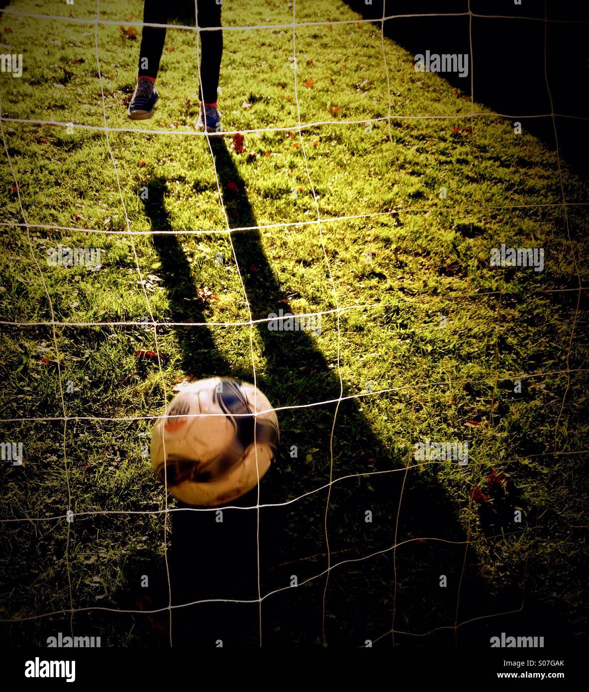 Schatten des Kindes treten Fußball auf Netz Stockfoto