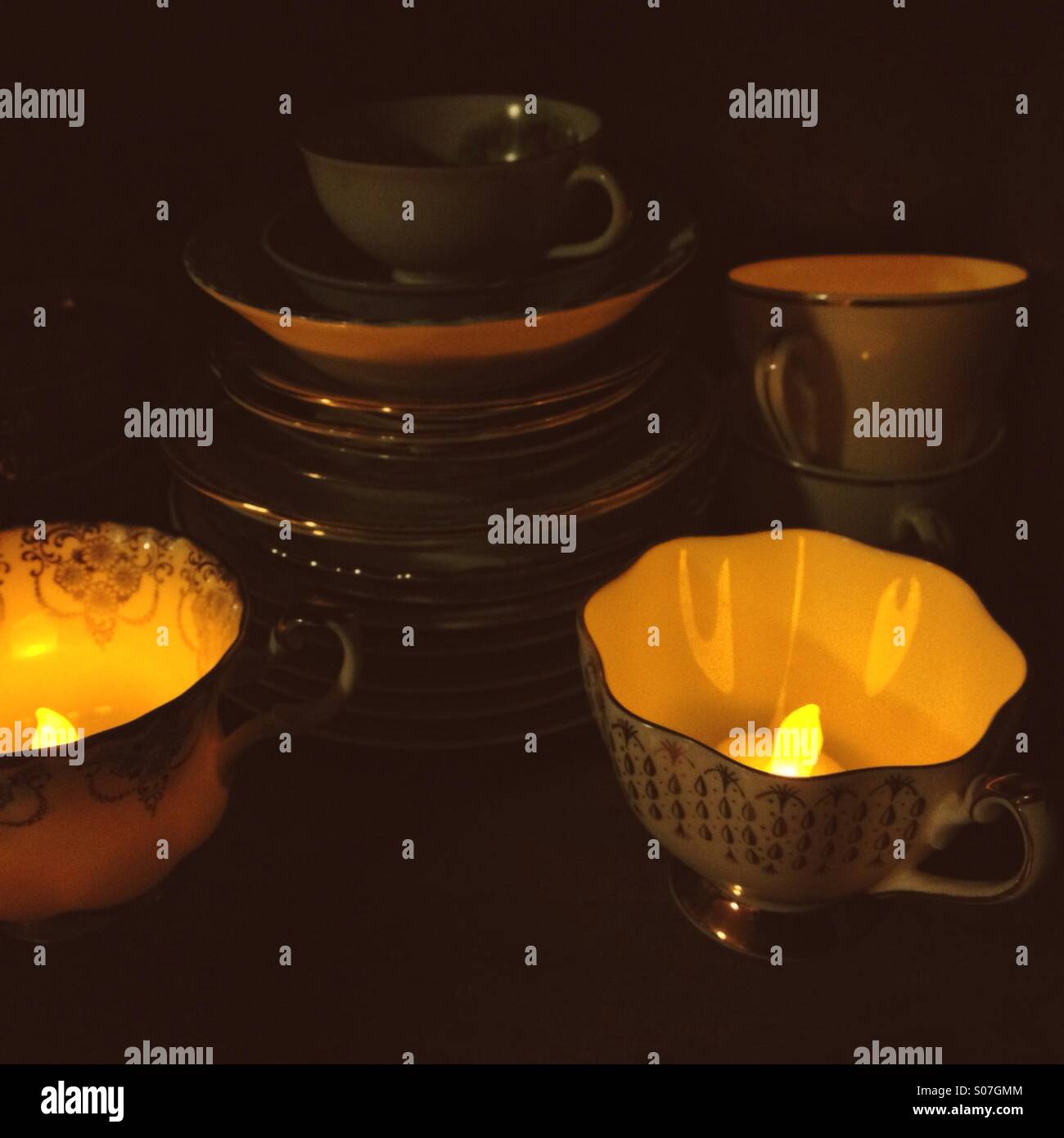 Teetassen auf einem Regal mit Teelichtern Glühen im Inneren. Stockfoto