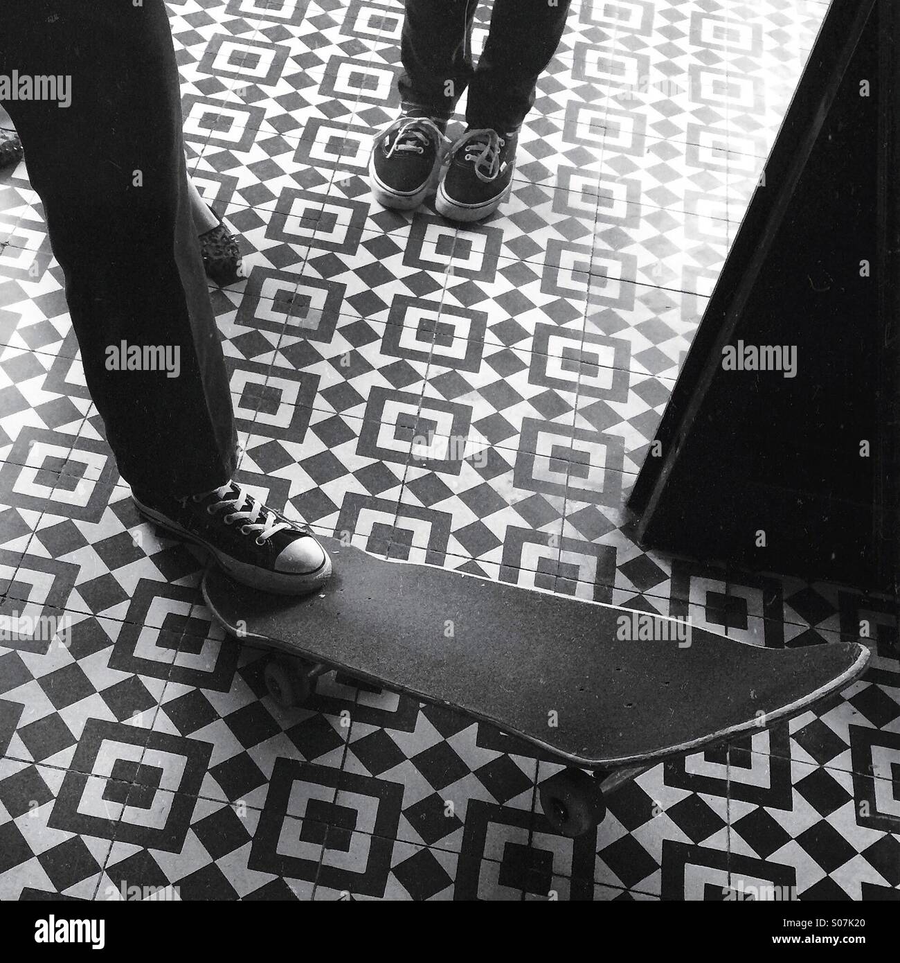 Schuhe und Skateboard auf einem Fliesenboden Stockfoto