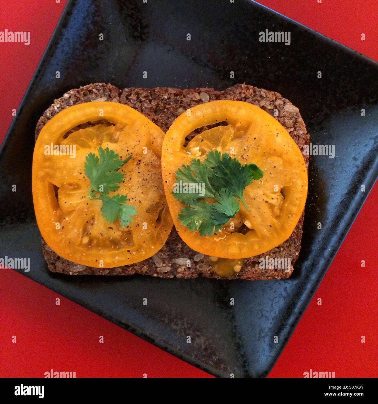 Gelbe Tomaten und Koriander auf Vollkornbrot. Stockfoto