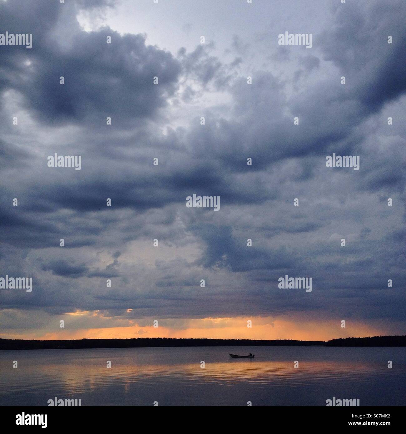 Ein Sommergewitter Mitternachtssonne nahe dem Polarkreis in Nordfinnland über ein Fischerboot auf einem riesigen See Stockfoto