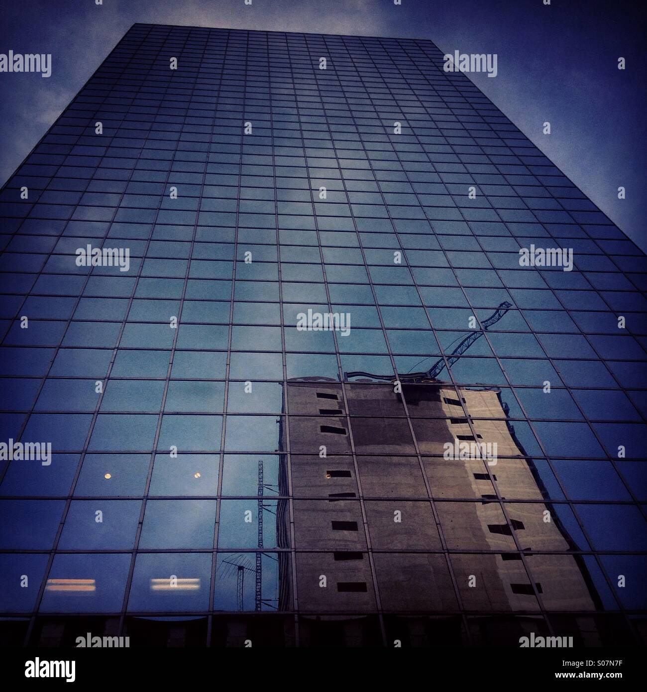 Eine Reflexion der Gebäude auf einem Wolkenkratzer in Reforma Avenue, Mexico City, Mexiko. Vögel sehen den Himmel spiegelt sich in den Fenstern und sterben krachte gegen das Glas. - Smartphone-aufgenommenes Stockfoto
