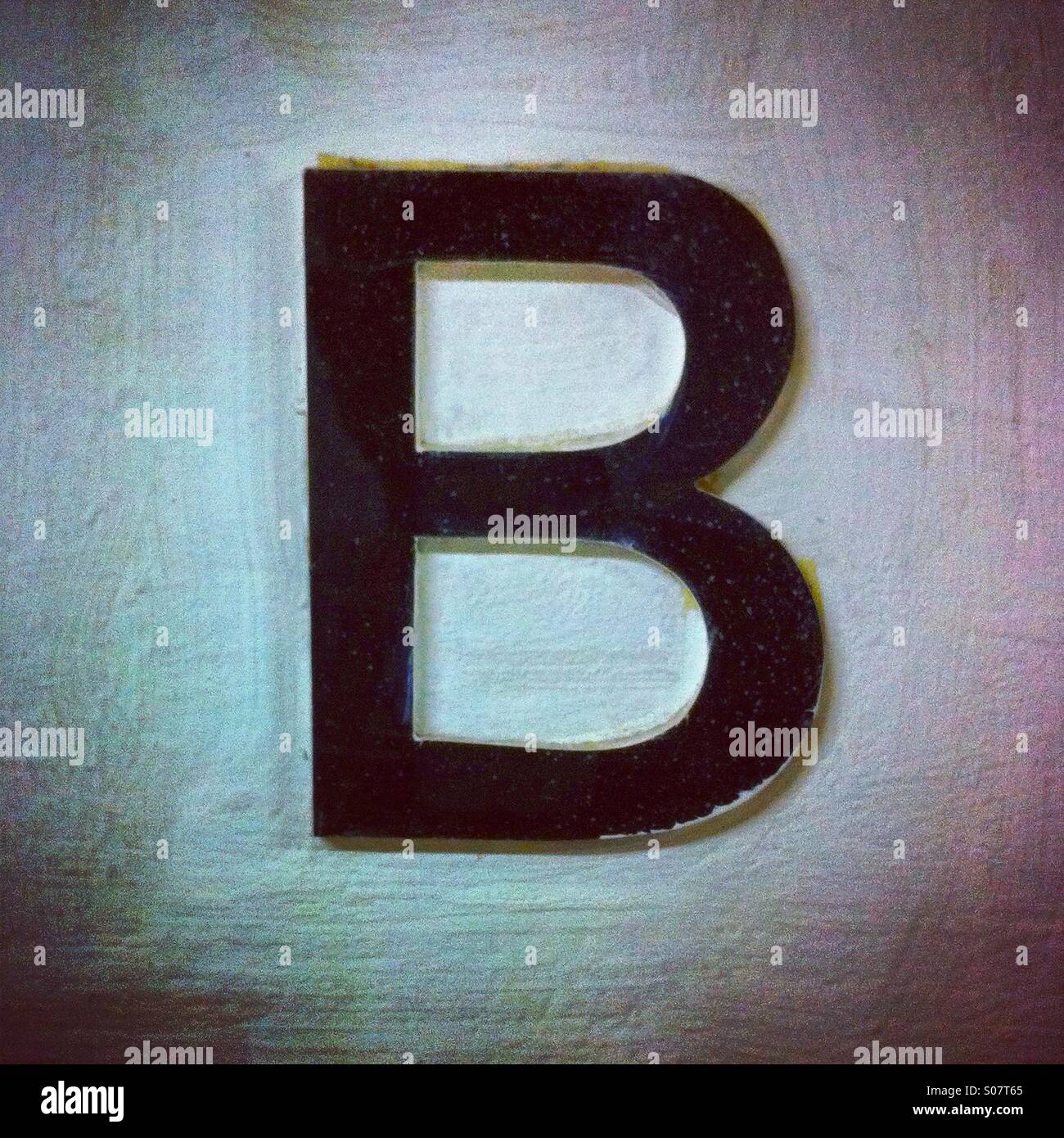 Buchstabe B in schwarzer Farbe an die Wand geklebt - Smartphone-aufgenommenes Stockfoto